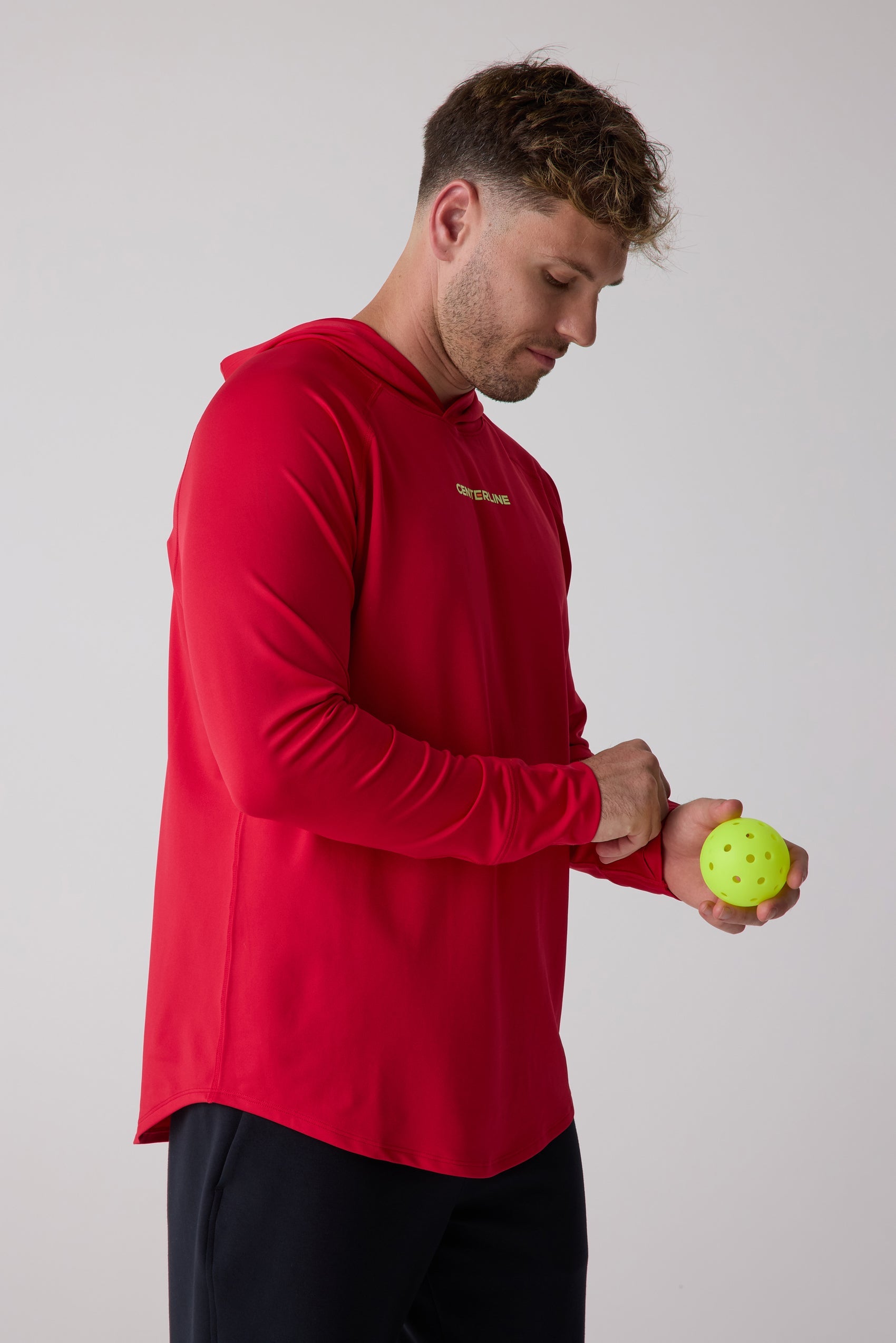 Red Men's Layering Hoodie by Centerline Athletics with a yellow chest logo, worn by a man holding a yellow pickleball.