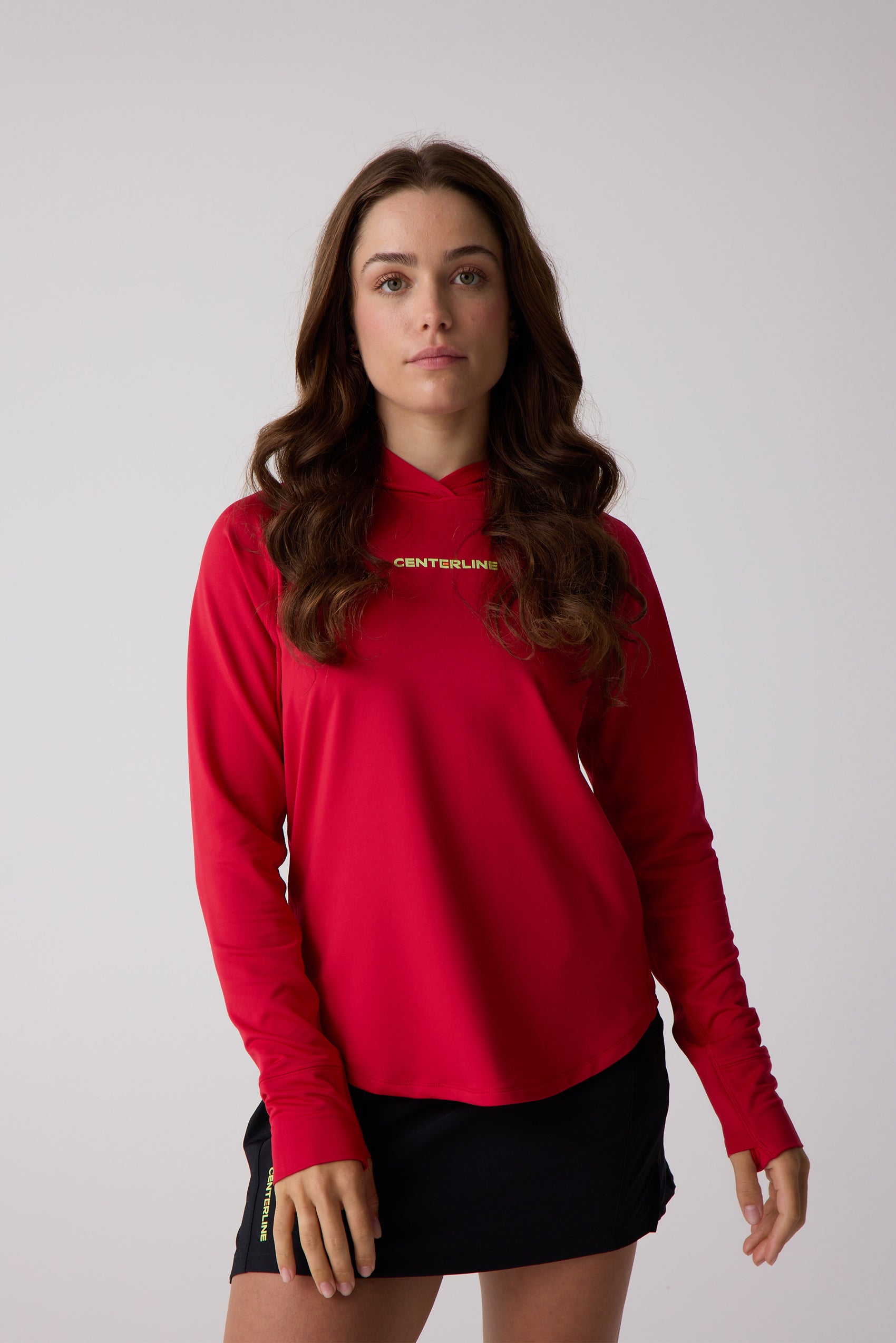 Red women's layering hoodie by Centerline Athletics, with a gold CENTERLINE logo and long sleeves with thumbholes, worn with black shorts.