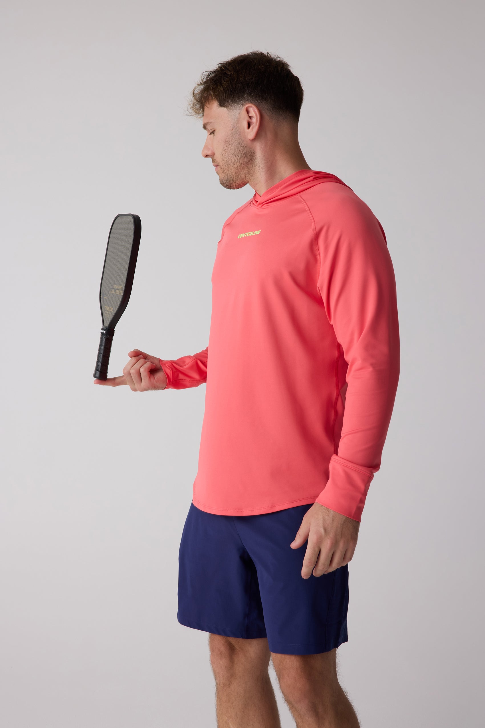 Men's coral layering hoodie by Centerline Athletics, worn by a man in navy shorts balancing a paddle on his finger.