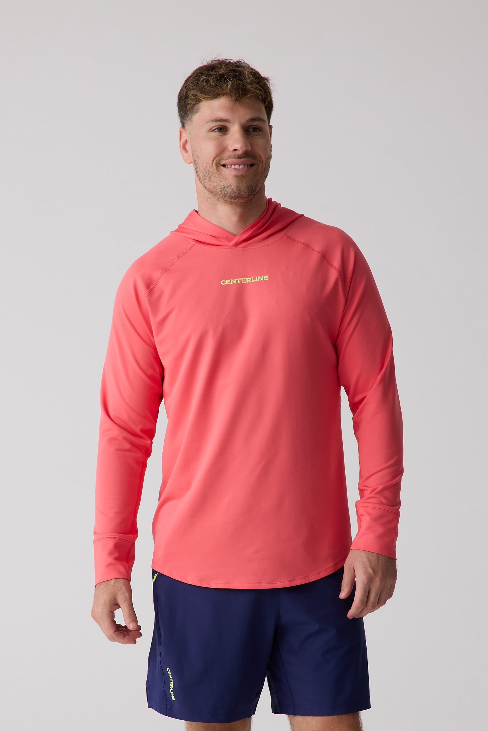 Coral men's layering hoodie from Centerline Athletics with yellow 'CENTERLINE' logo on chest, worn with navy shorts.