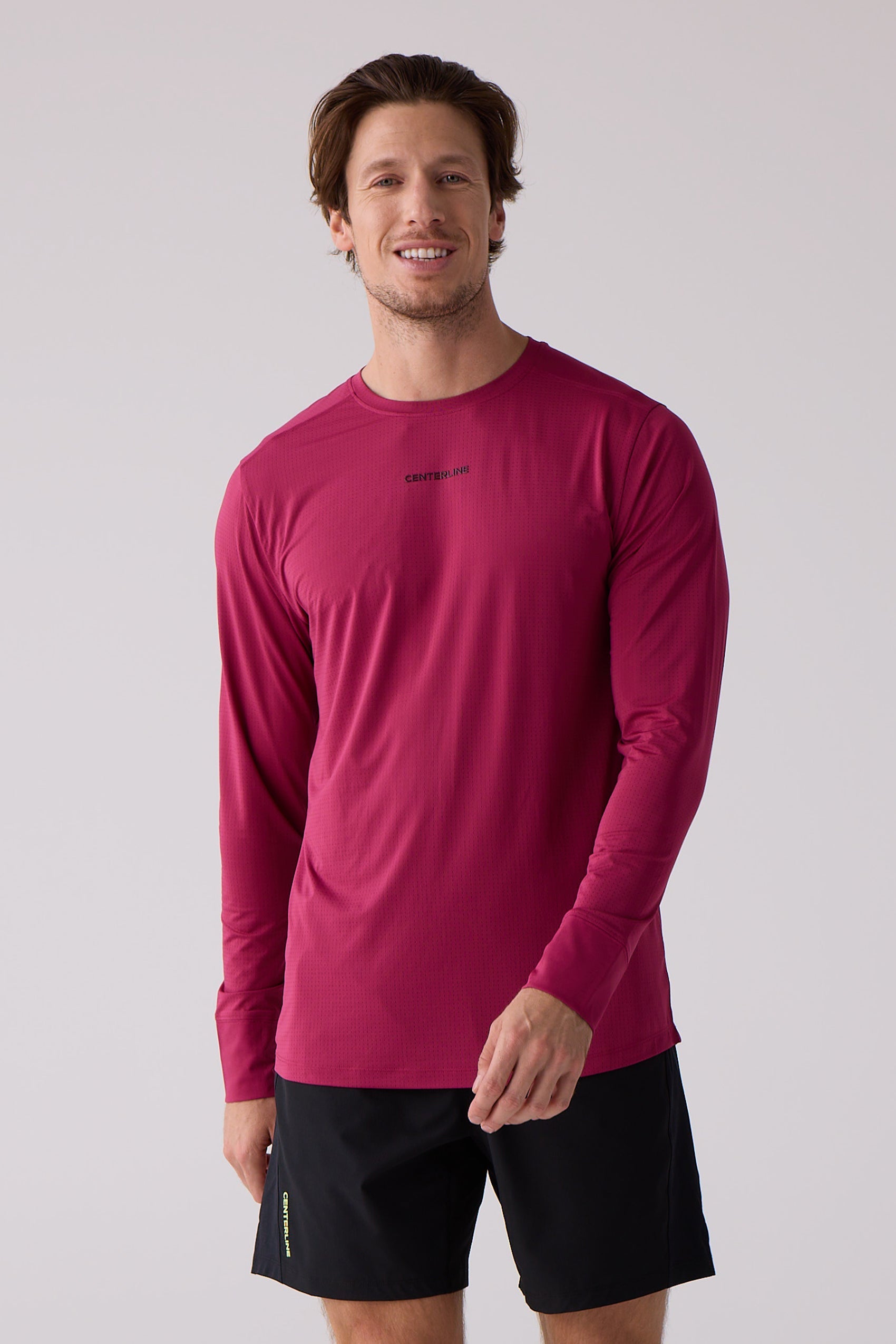 Dark pink men's long sleeve shirt by Centerline Athletics featuring a subtle grid pattern, "CENTERLINE" text, and thumbholes, worn with black shorts.