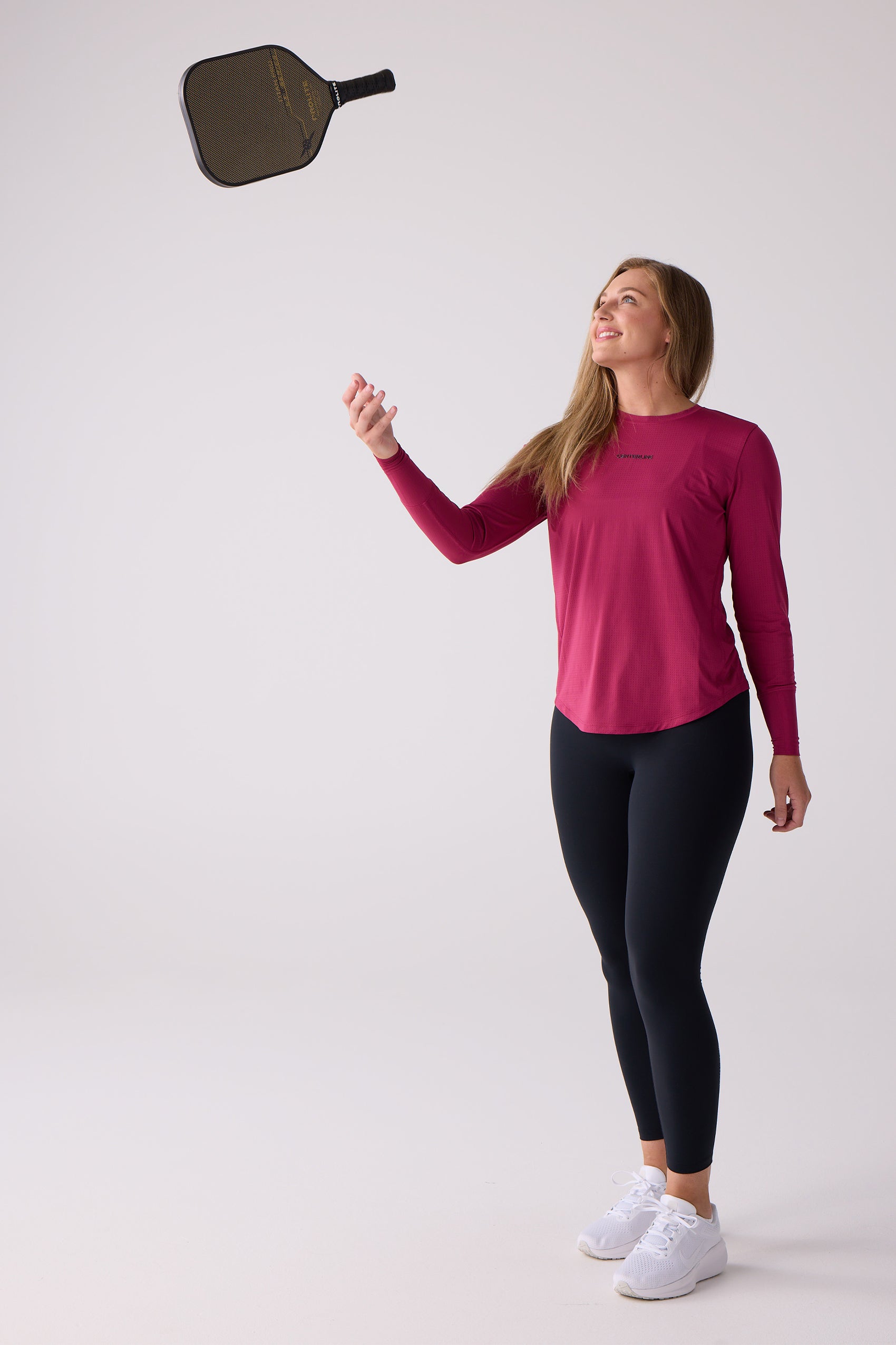 Fuchsia women's long sleeve shirt by Centerline Athletics, with a subtle perforated texture, worn with black leggings.