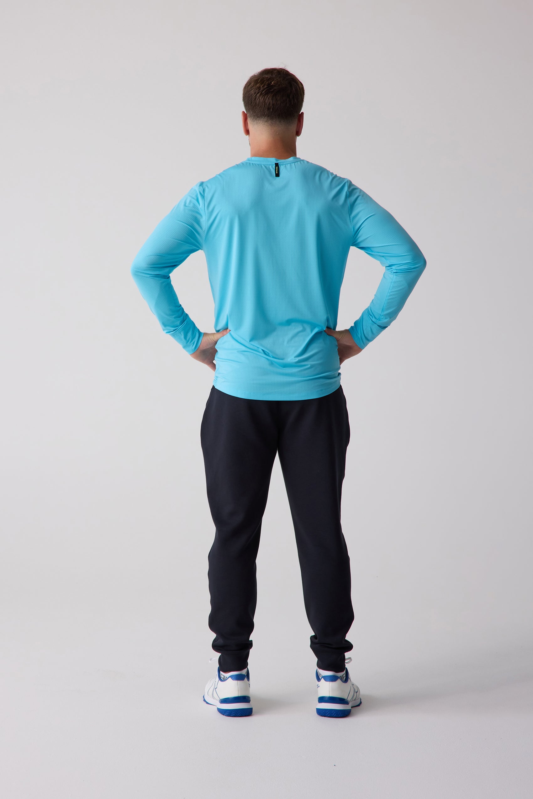 Men's AirLite Long Sleeve light blue shirt by Centerline Athletics, with micro-dot texture, worn from the back with dark pants and white sneakers.