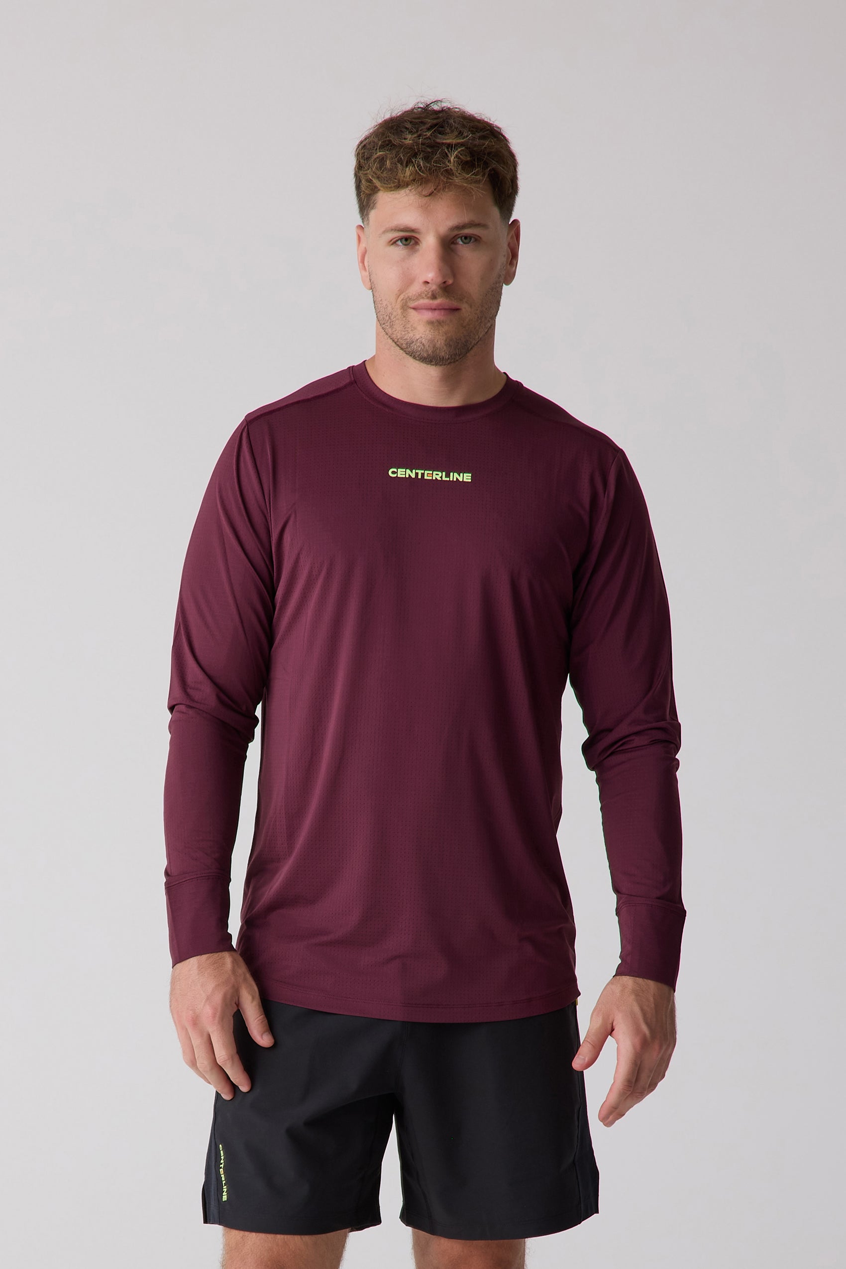 Burgundy men's AirLite long sleeve by Centerline Athletics, with a perforated texture and lime green chest logo, worn with black shorts.