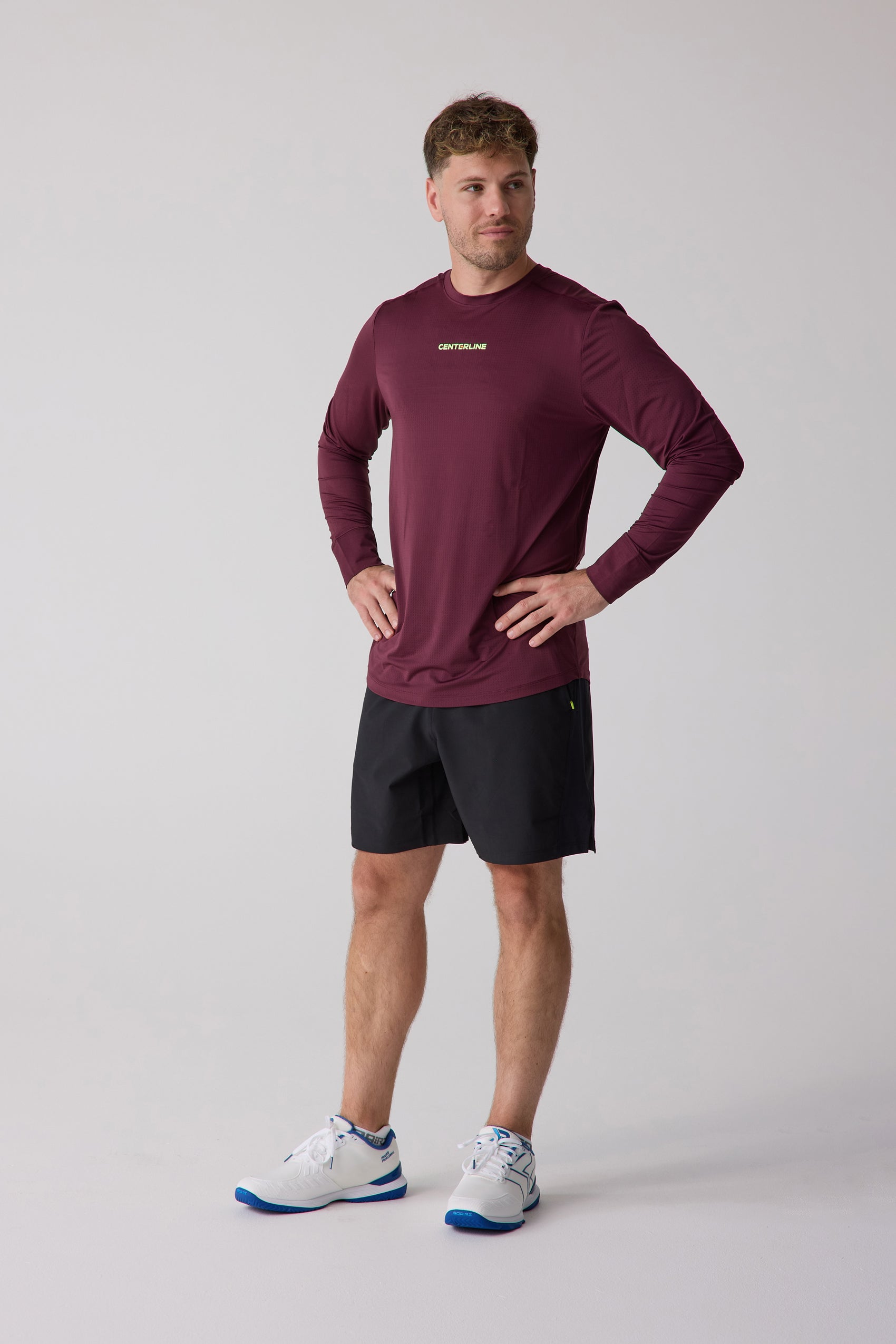 Maroon long sleeve athletic shirt by Centerline Athletics, with textured fabric, worn by a man in black shorts and white shoes.