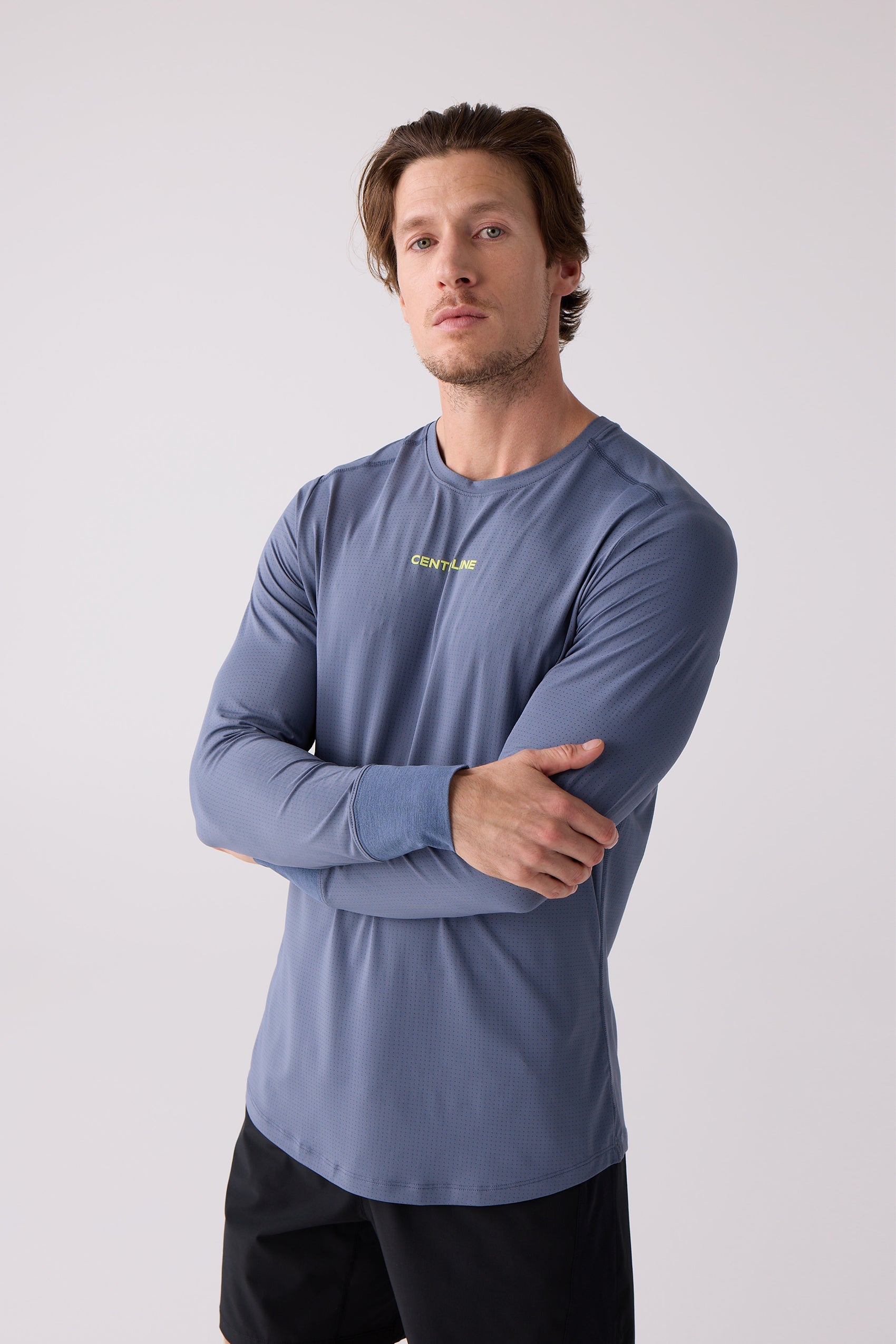 Blue long sleeve shirt by Centerline Athletics with perforated fabric, yellow 'CENT/LINE' logo, and cuffed sleeves, worn with black shorts.