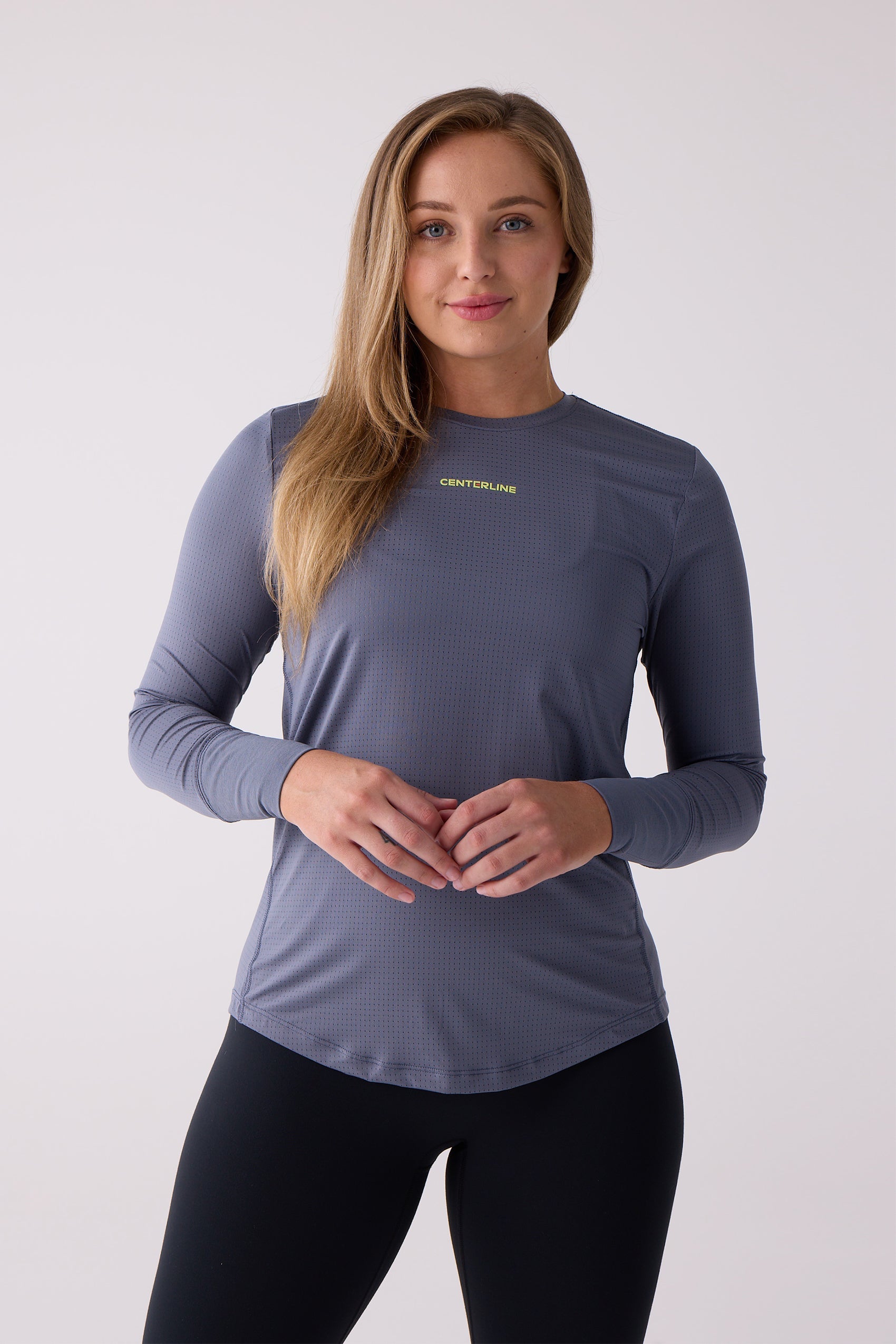 Women's dark blue-grey AirLite long sleeve shirt by Centerline Athletics, with a perforated texture and lime green logo, worn with black leggings.