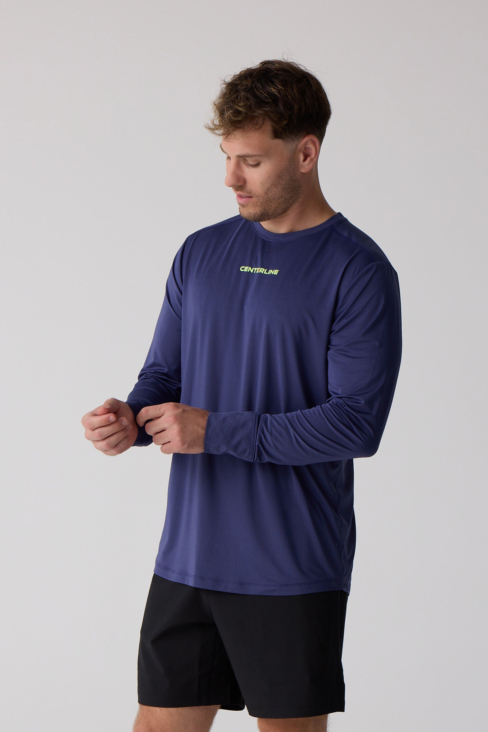 Men's dark blue AirLite long sleeve shirt by Centerline Athletics, featuring a textured finish and lime green chest logo, worn with black shorts.