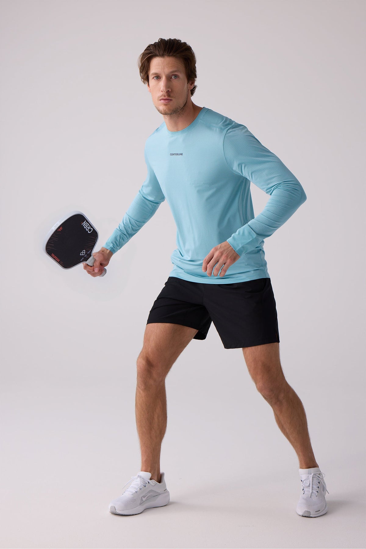 Light blue men's long sleeve performance shirt by Centerline, featuring textured fabric and small chest logo, shown in lifestyle pose with paddle.