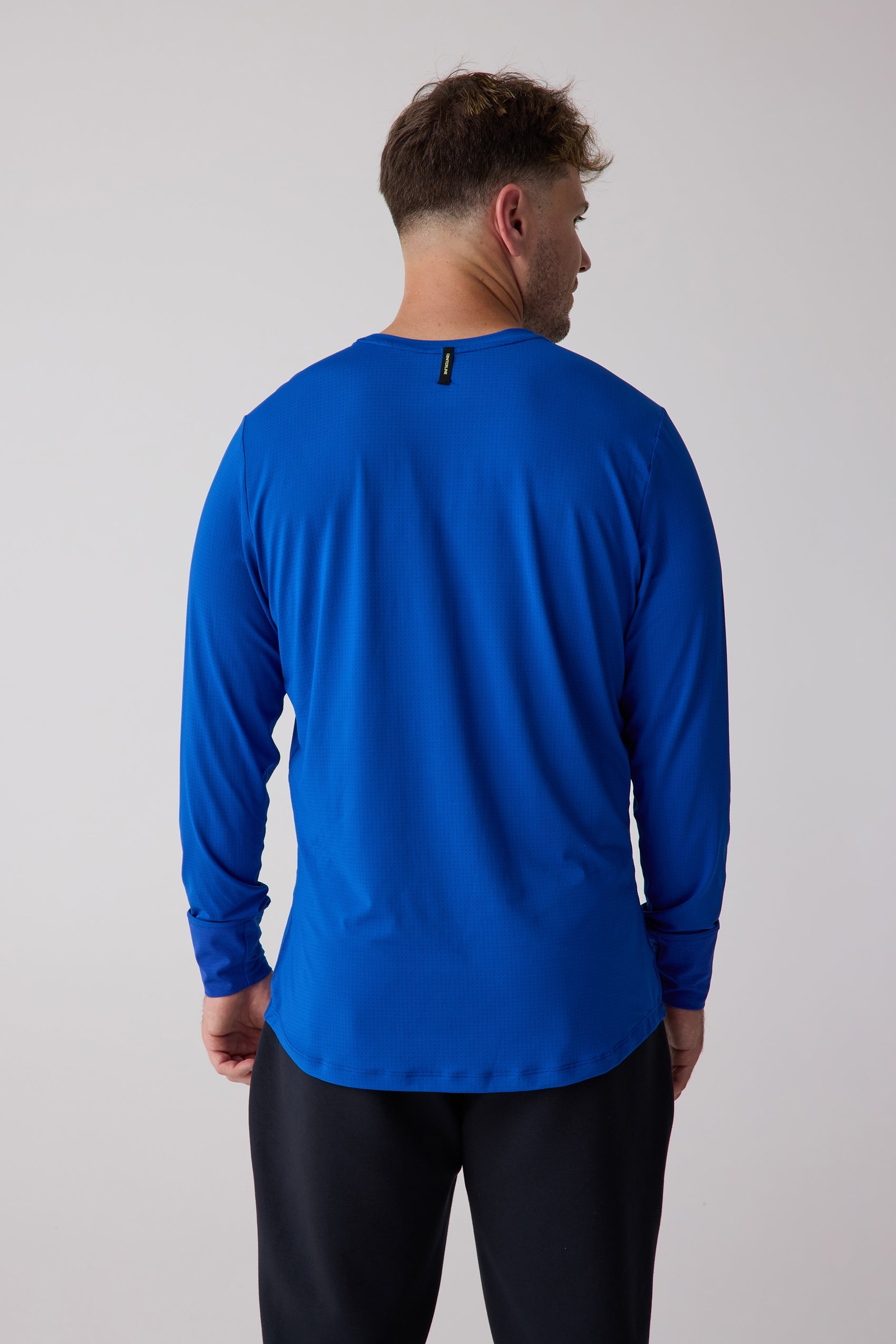 Blue men's long sleeve shirt by Centerline Athletics, featuring a subtle grid texture, shown from the back with black athletic pants.