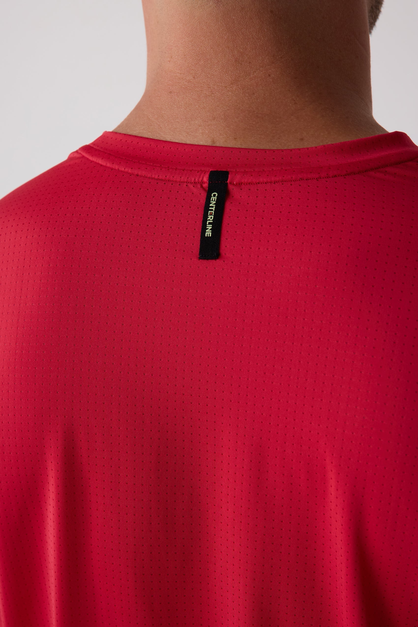 Red Men's AirLite Long Sleeve by Centerline Athletics, featuring a perforated texture and a black 'CENTERLINE' tag on the upper back.