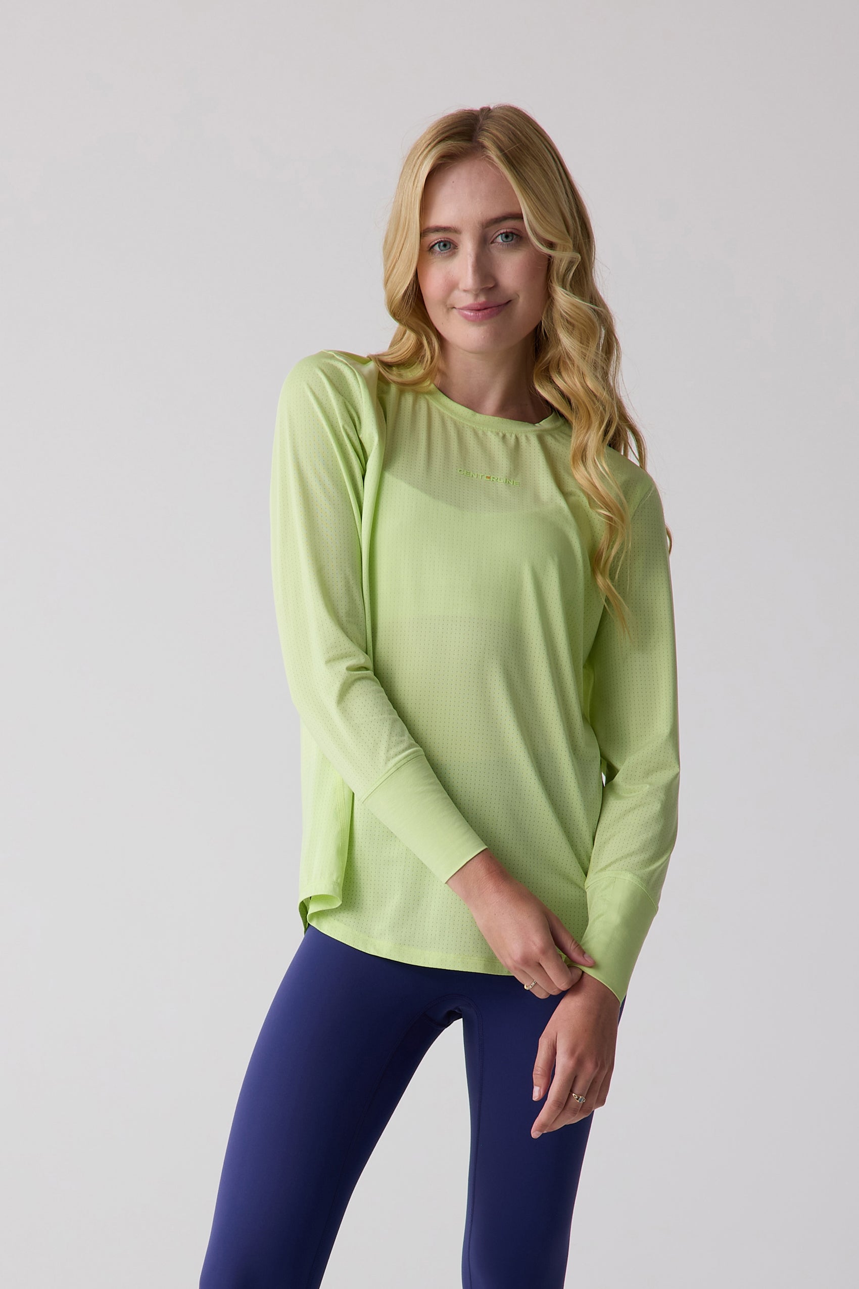 Lime green perforated women's long sleeve shirt by Centerline Athletics, worn with navy blue leggings.