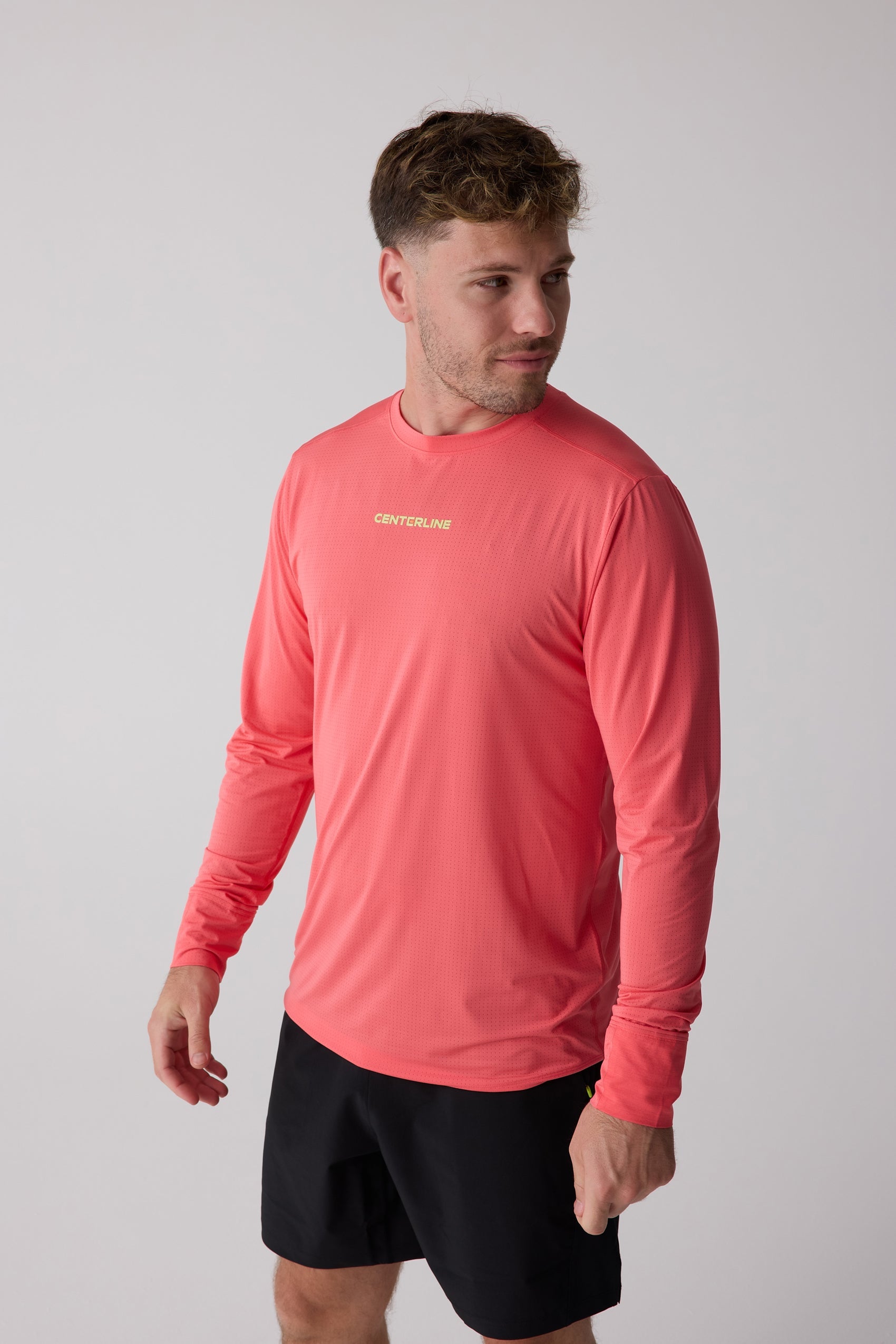 Coral perforated Men's AirLite Long Sleeve by Centerline Athletics, featuring "CENTERLINE" logo on chest, worn by a man in black shorts.