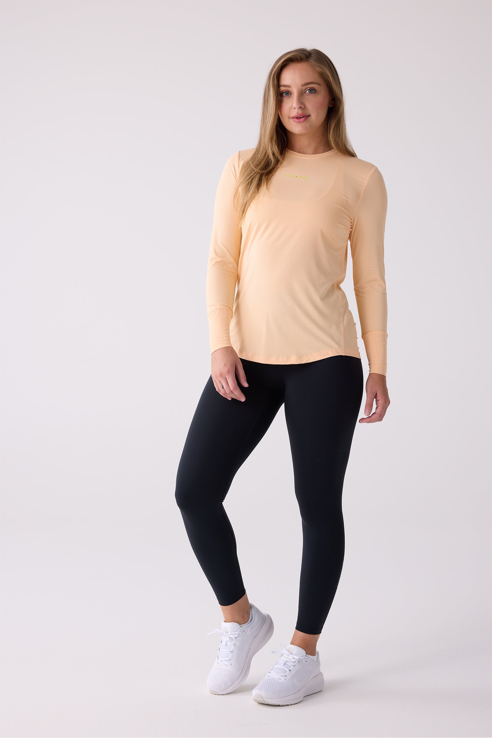 Peach AirLite Long Sleeve Shirt by Centerline Athletics, featuring a subtle dotted texture and yellow text logo, worn with black leggings.