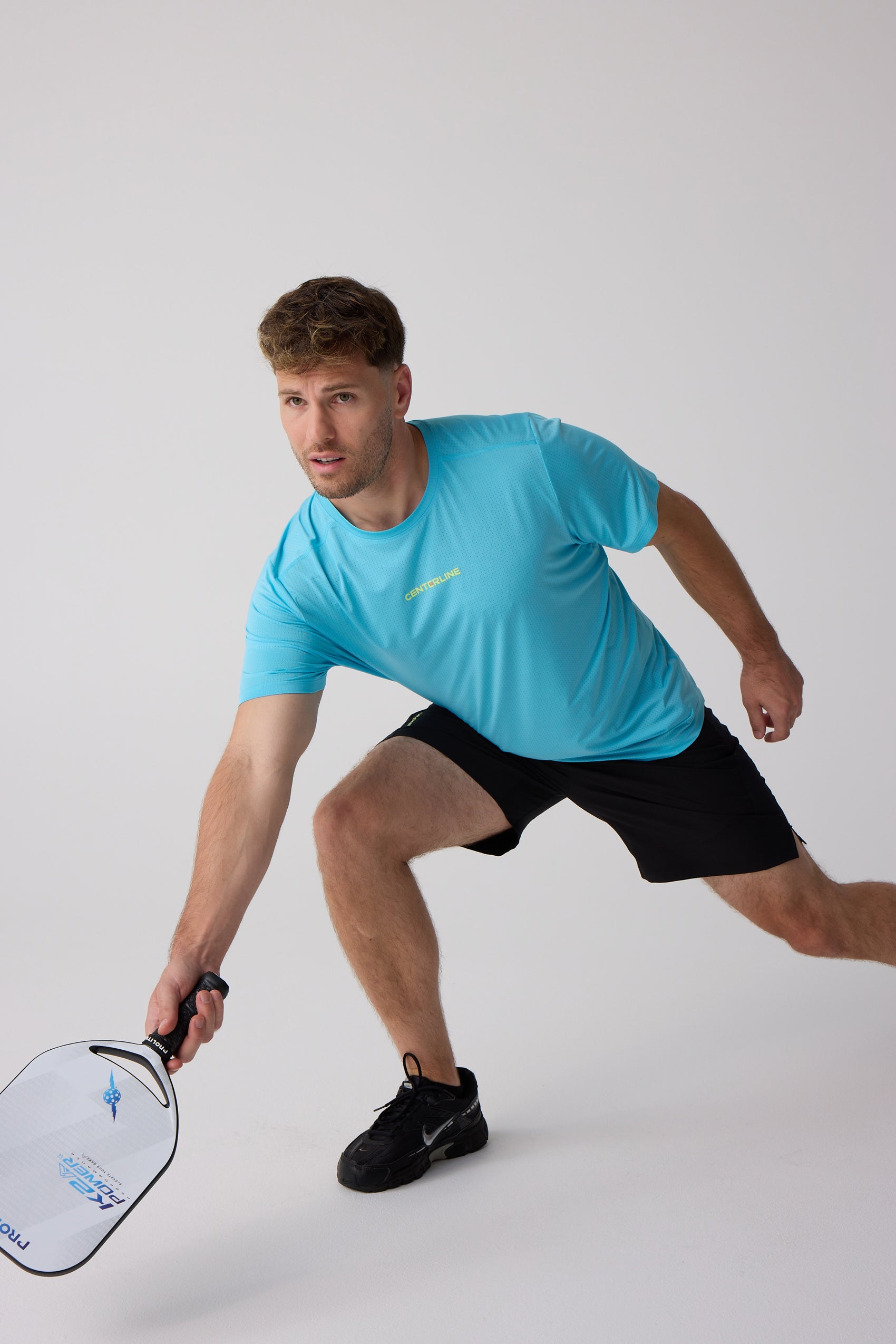 Black Men's AirLite 7" Unlined Short by Centerline Athletics, worn by a man in an athletic pose holding a paddle.