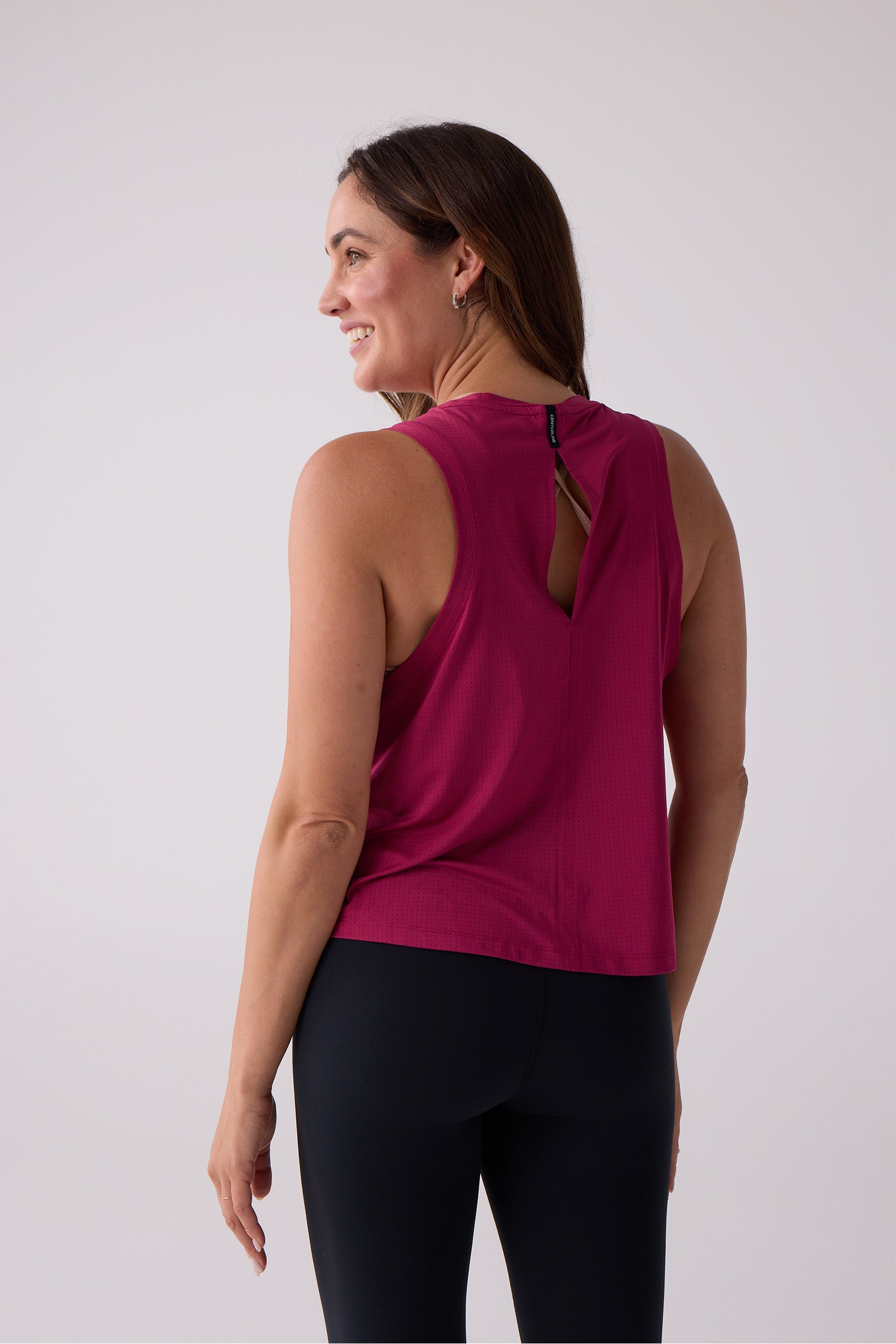 Fuchsia AirLite tank top by Centerline Athletics with a keyhole back detail and subtle perforations, worn with black leggings.