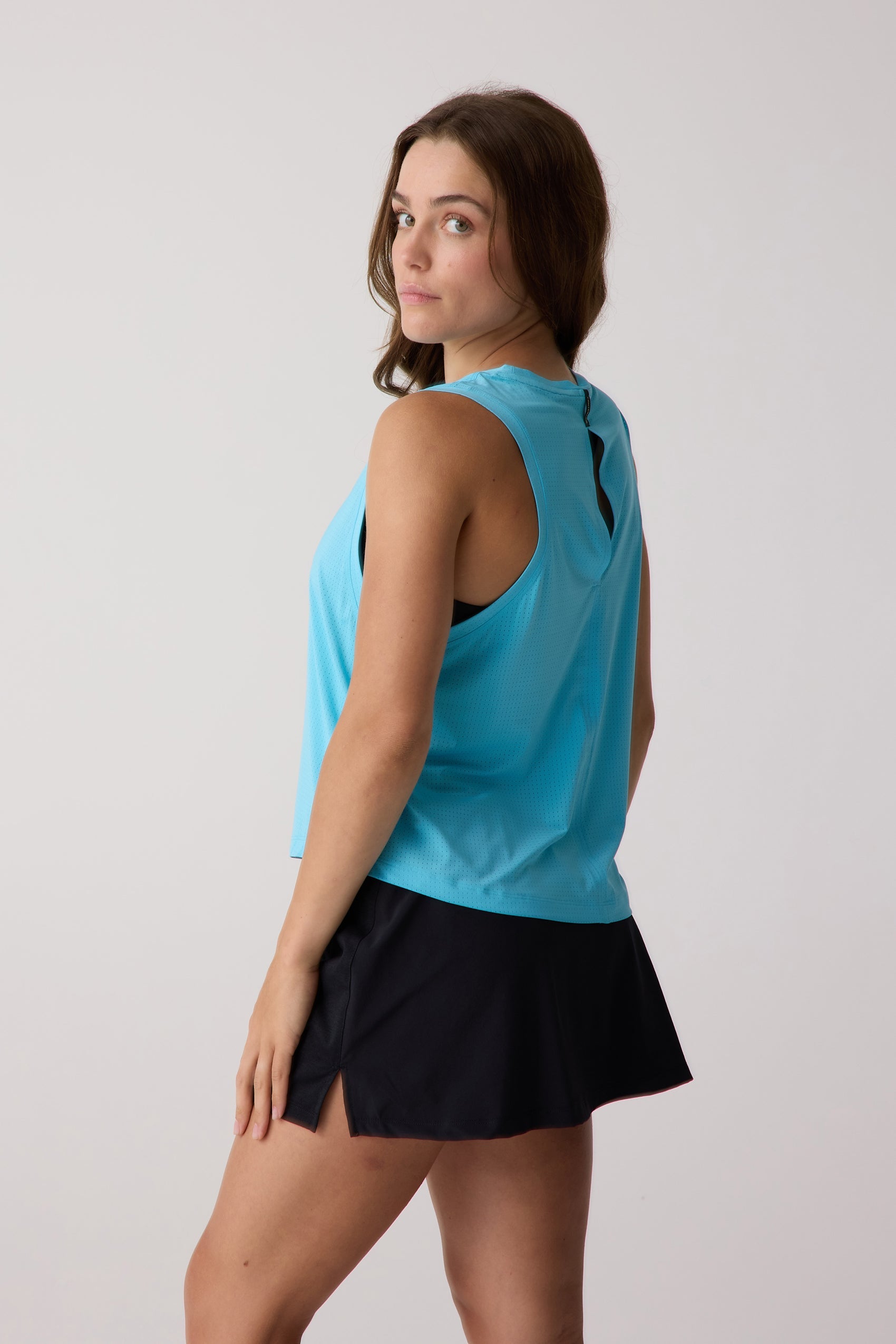 Women's aqua AirLite tank by Centerline Athletics, featuring perforated fabric and a back keyhole cutout, worn with a black skirt.