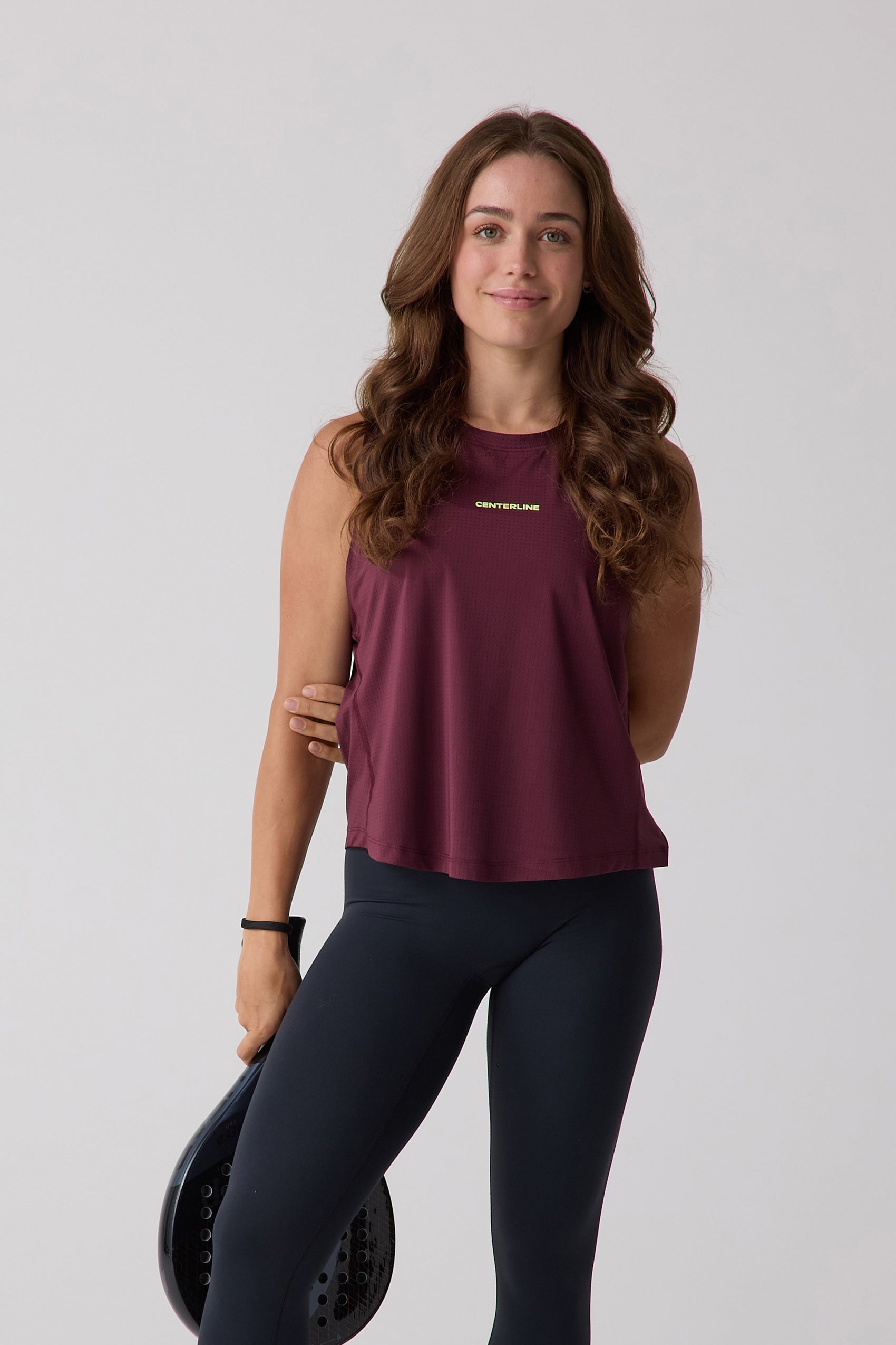 Maroon sleeveless tank top by Centerline Athletics with perforated fabric, worn by a woman in black leggings holding a paddle.