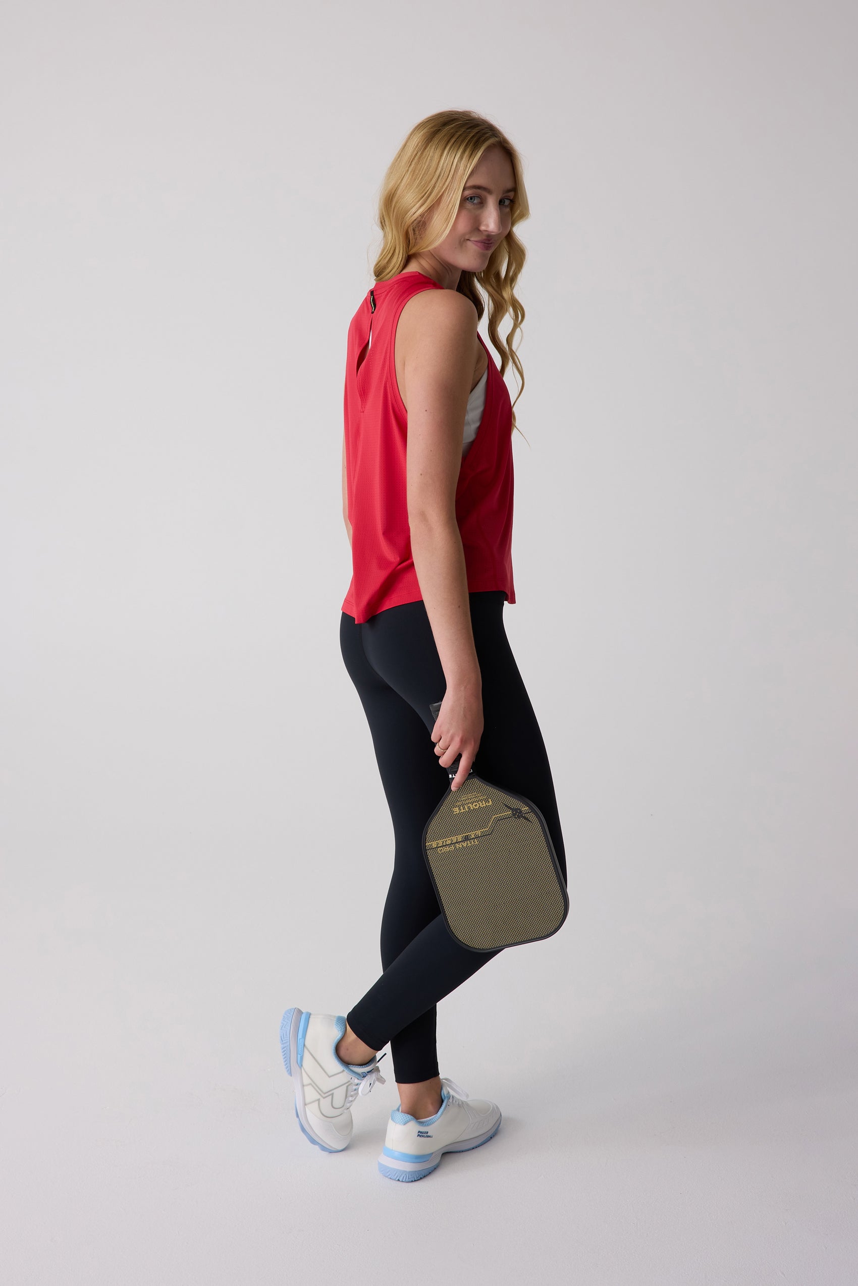 Red perforated women's tank top from Centerline Athletics, with a subtle back cutout, worn with black leggings.