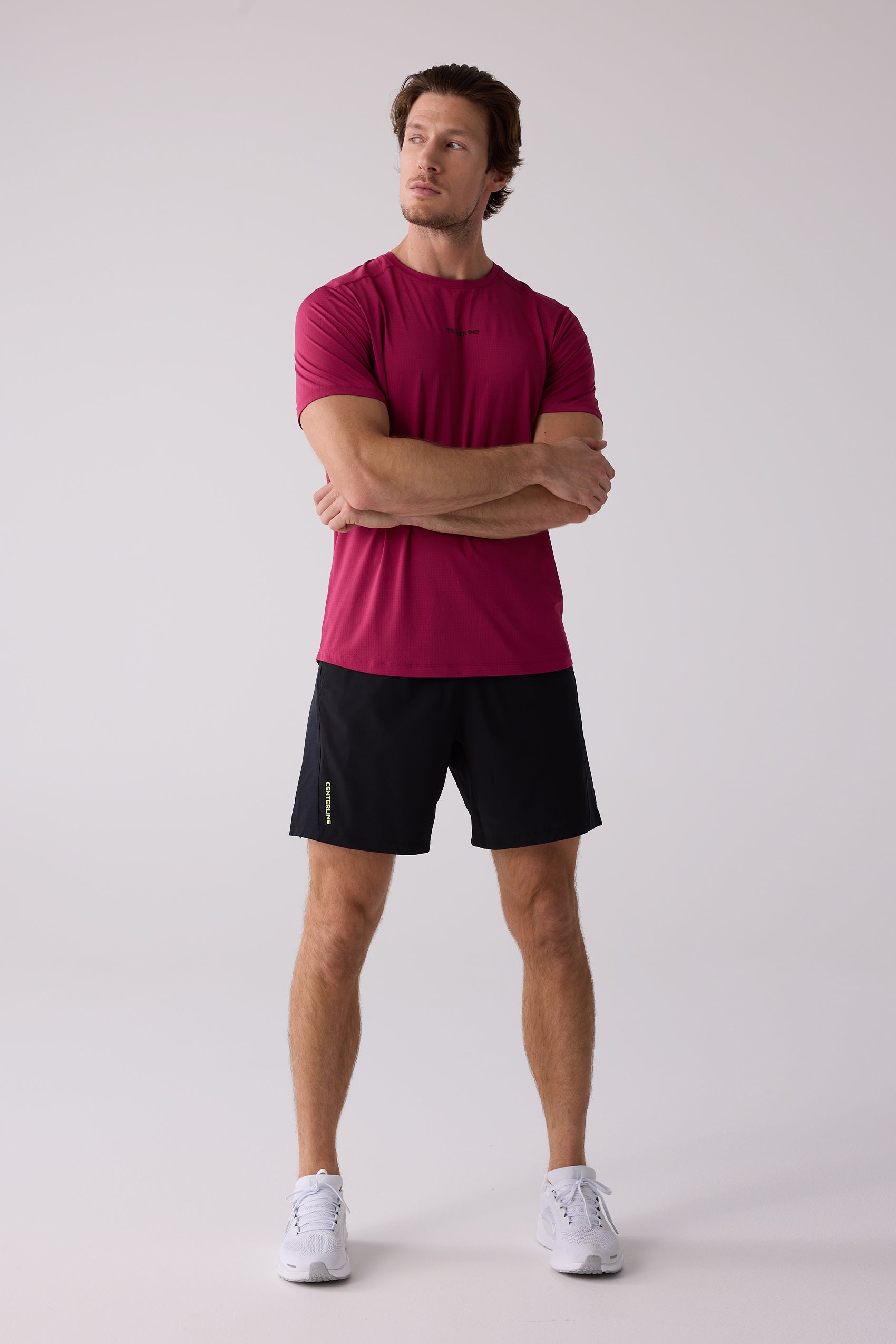 Deep red men's AirLite tee by Centerline Athletics with subtle texture and tonal chest logo, worn with black shorts and white athletic shoes.