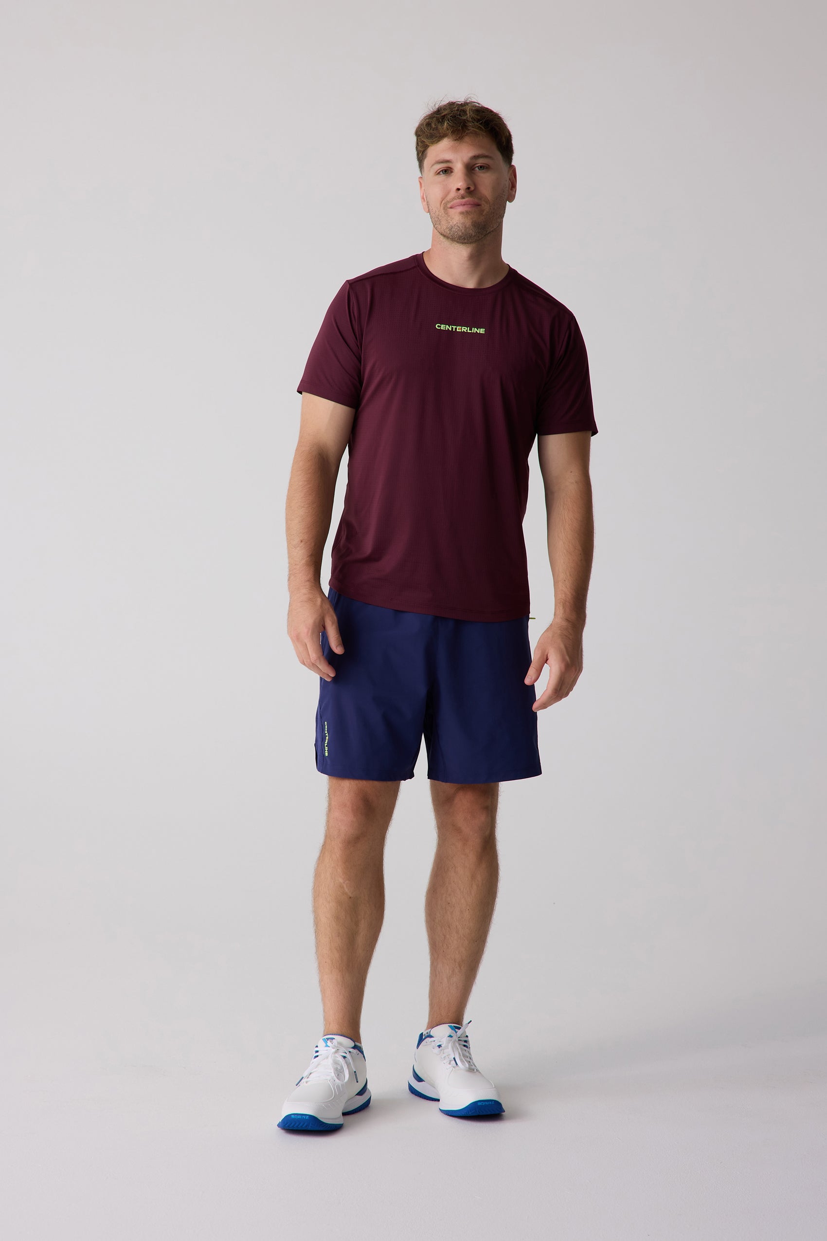Maroon Men's AirLite Tee by Centerline Athletics with a lime green logo, styled with navy shorts and white athletic shoes.