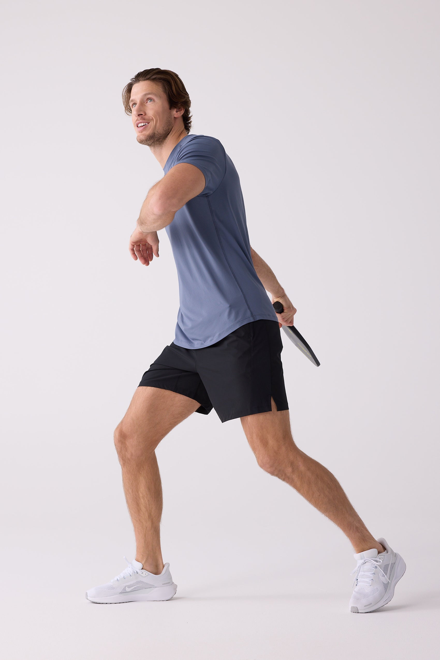 Dusty blue textured Men's AirLite Tee by Centerline Athletics, worn by a man with black shorts and white athletic shoes playing a paddle sport.