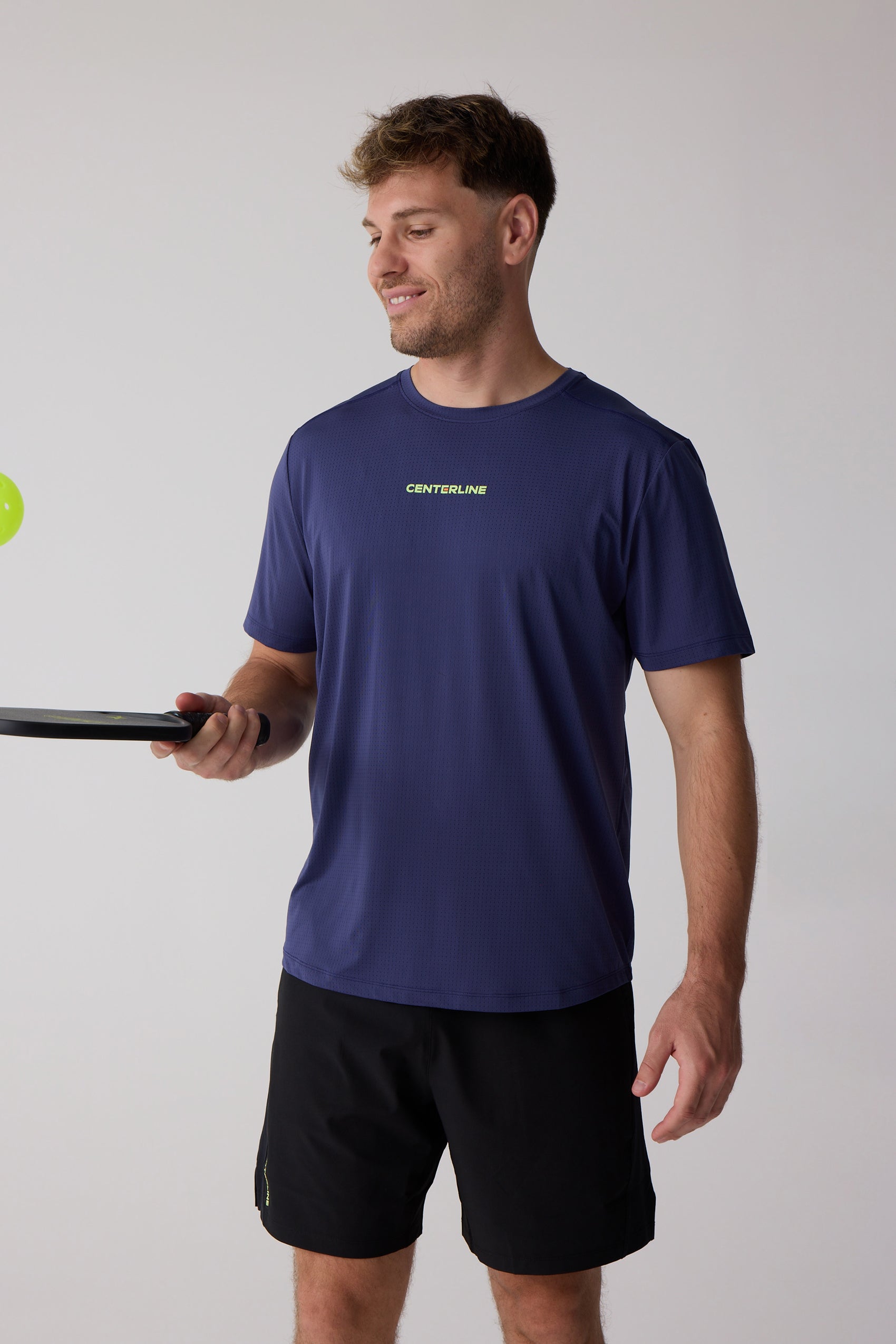Navy performance t-shirt by Centerline Athletics with tiny perforations, lime green chest text, worn by a man holding a paddle.