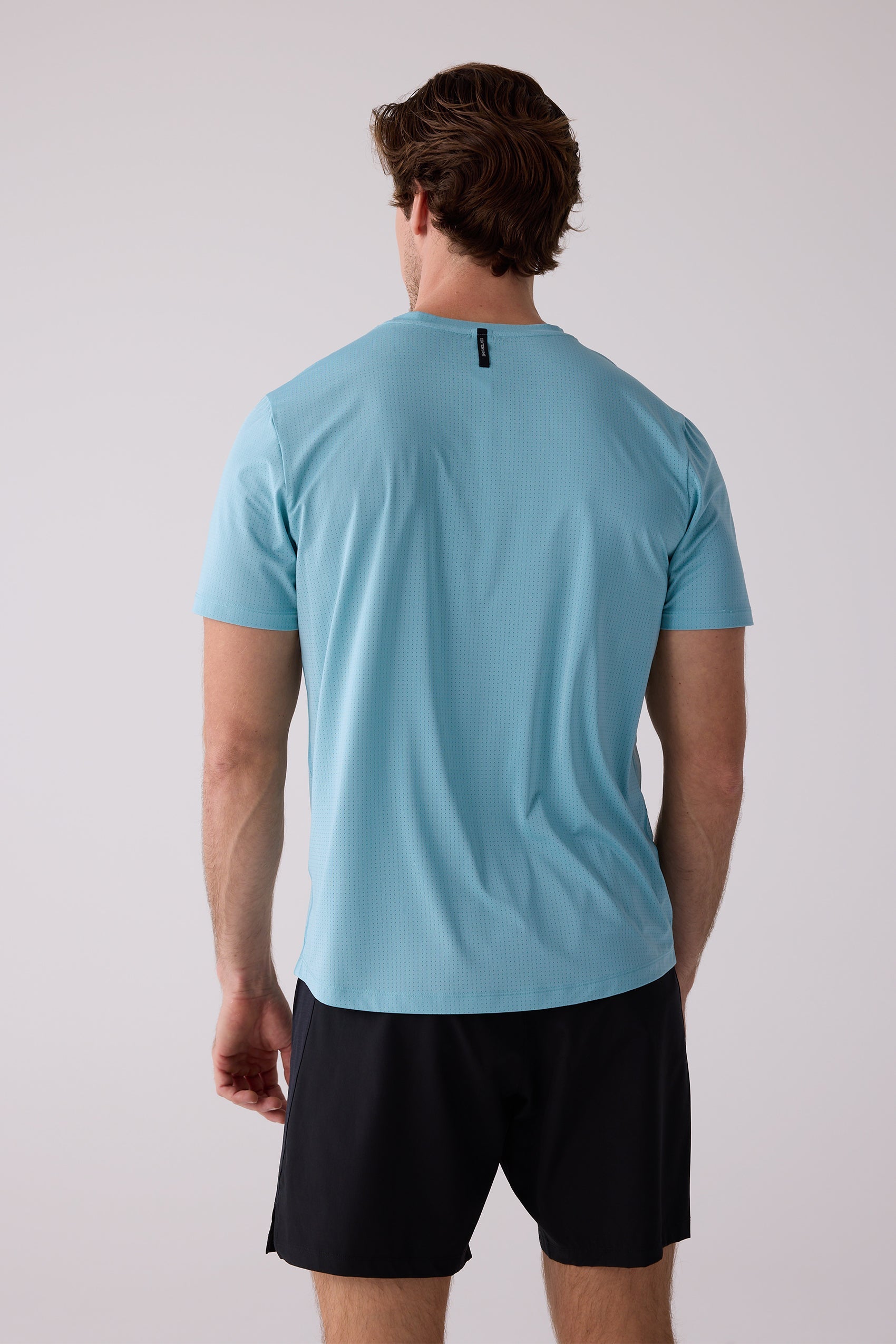 Light blue perforated men's AirLite tee by Centerline Athletics, back view, featuring a small black tag at the neckline.