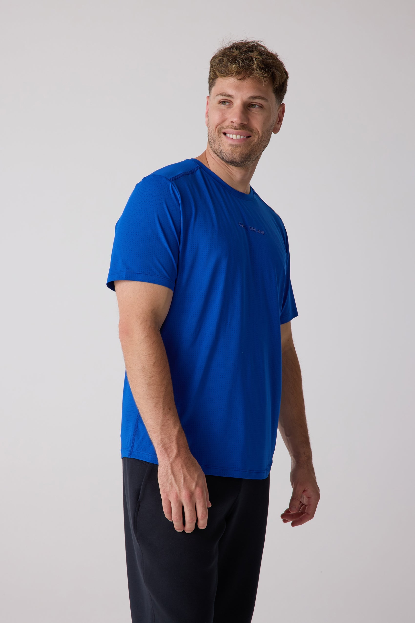 Blue men's AirLite tee by Centerline Athletics with subtle textured fabric, featuring a 'CENTERLINE' logo on the chest, worn by a man in black pants.