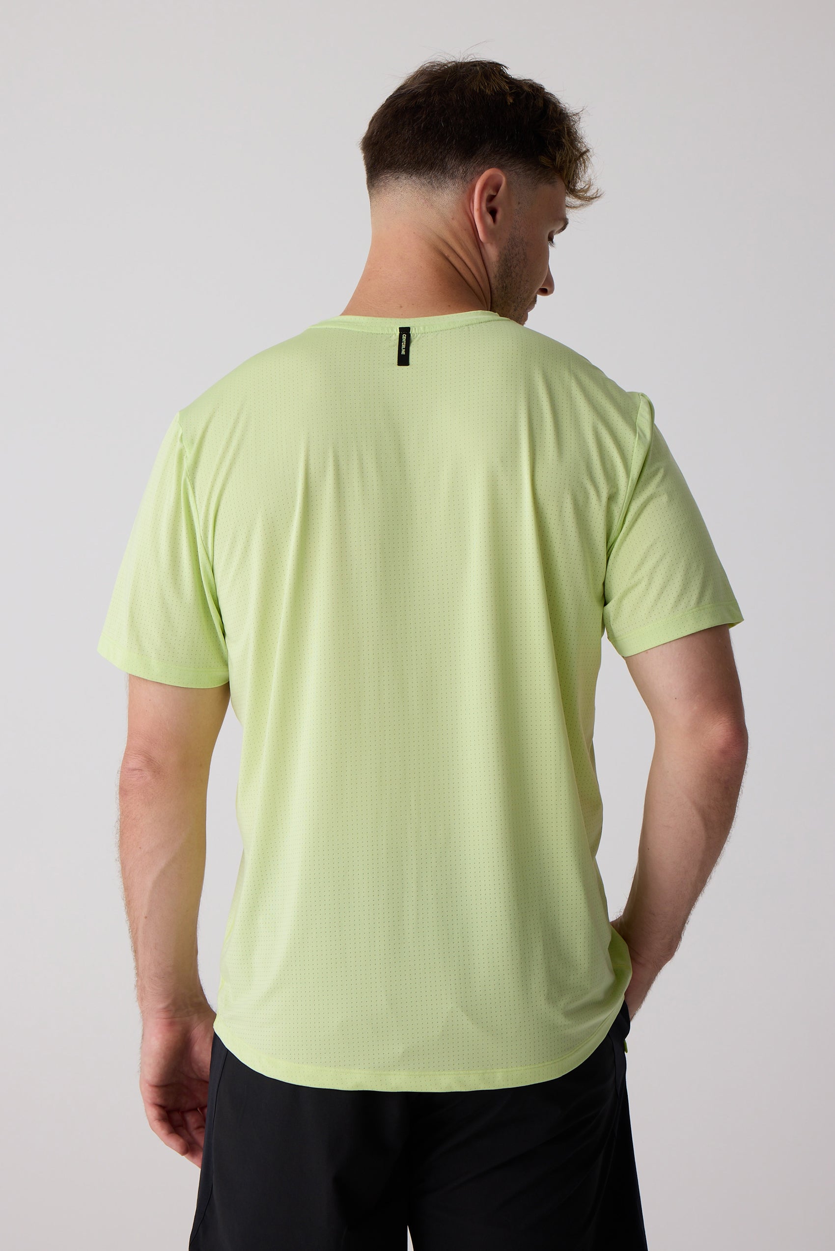 Light green men's tee by Centerline Athletics, with subtle perforations and a black neck tag, shown from the back.