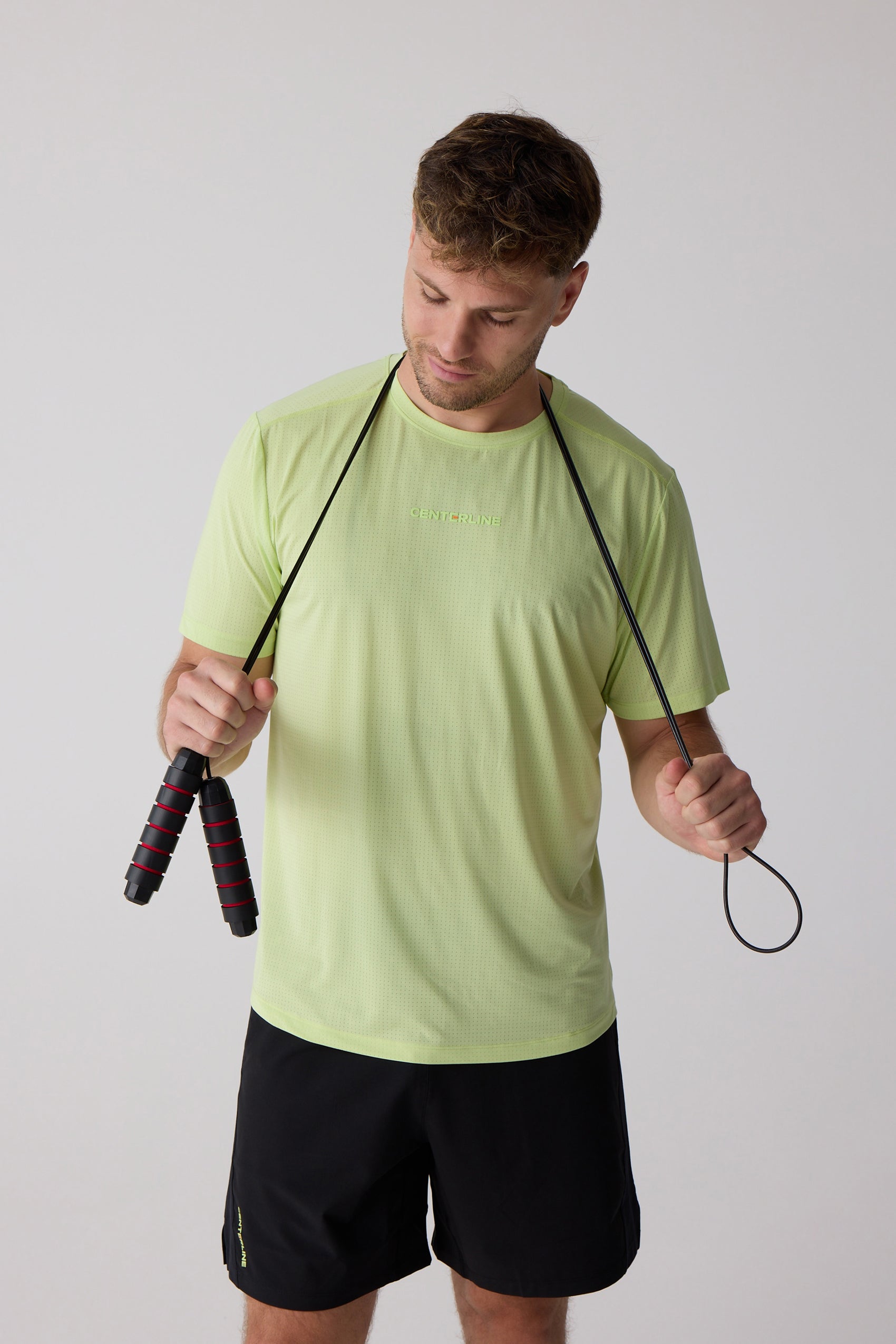 Lime green AirLite tee by Centerline Athletics, featuring perforated fabric and chest logo, worn by a man holding a jump rope.