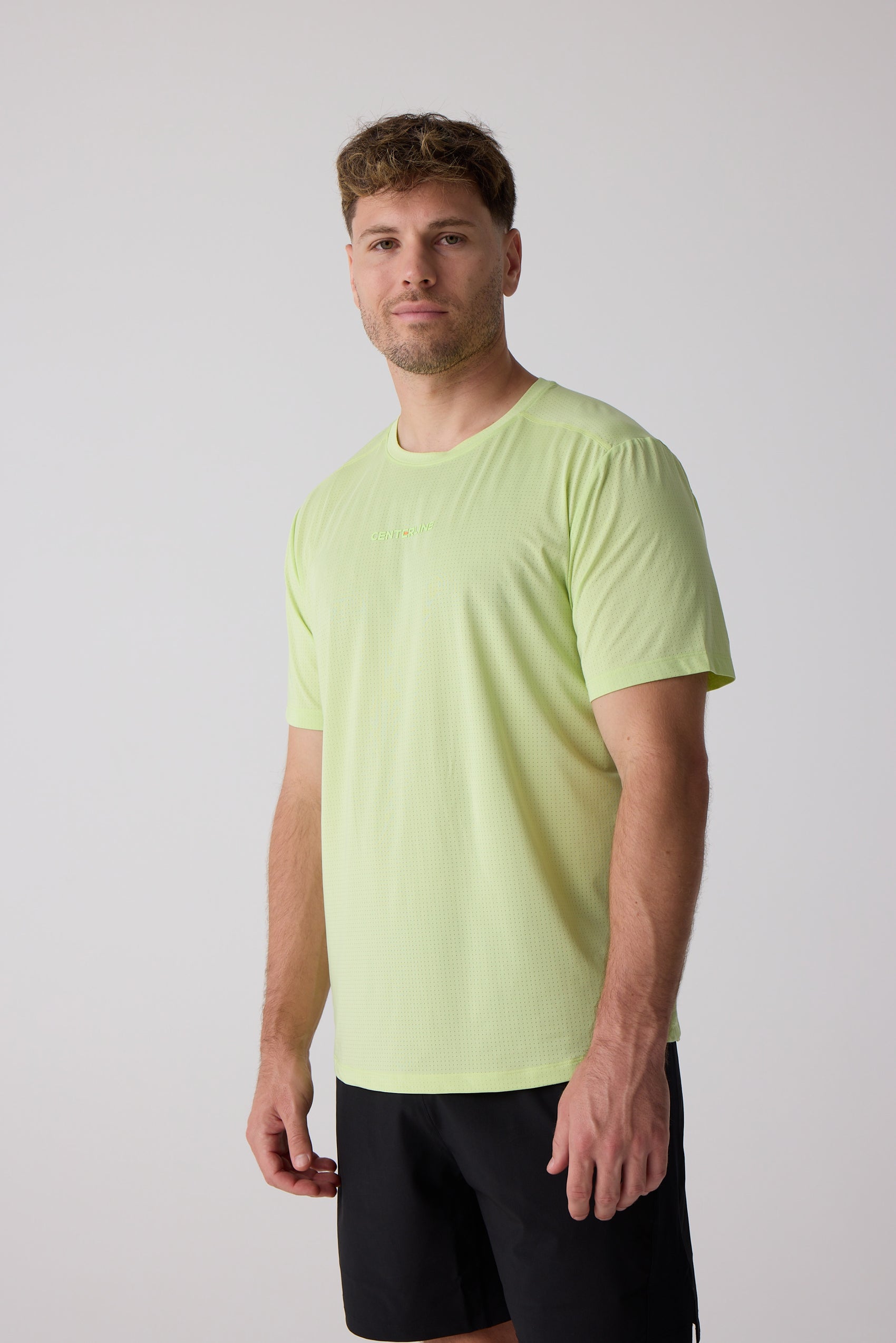 Lime green Men's AirLite Tee by Centerline Athletics, featuring a subtle perforated texture and short sleeves, worn by a man in black shorts.