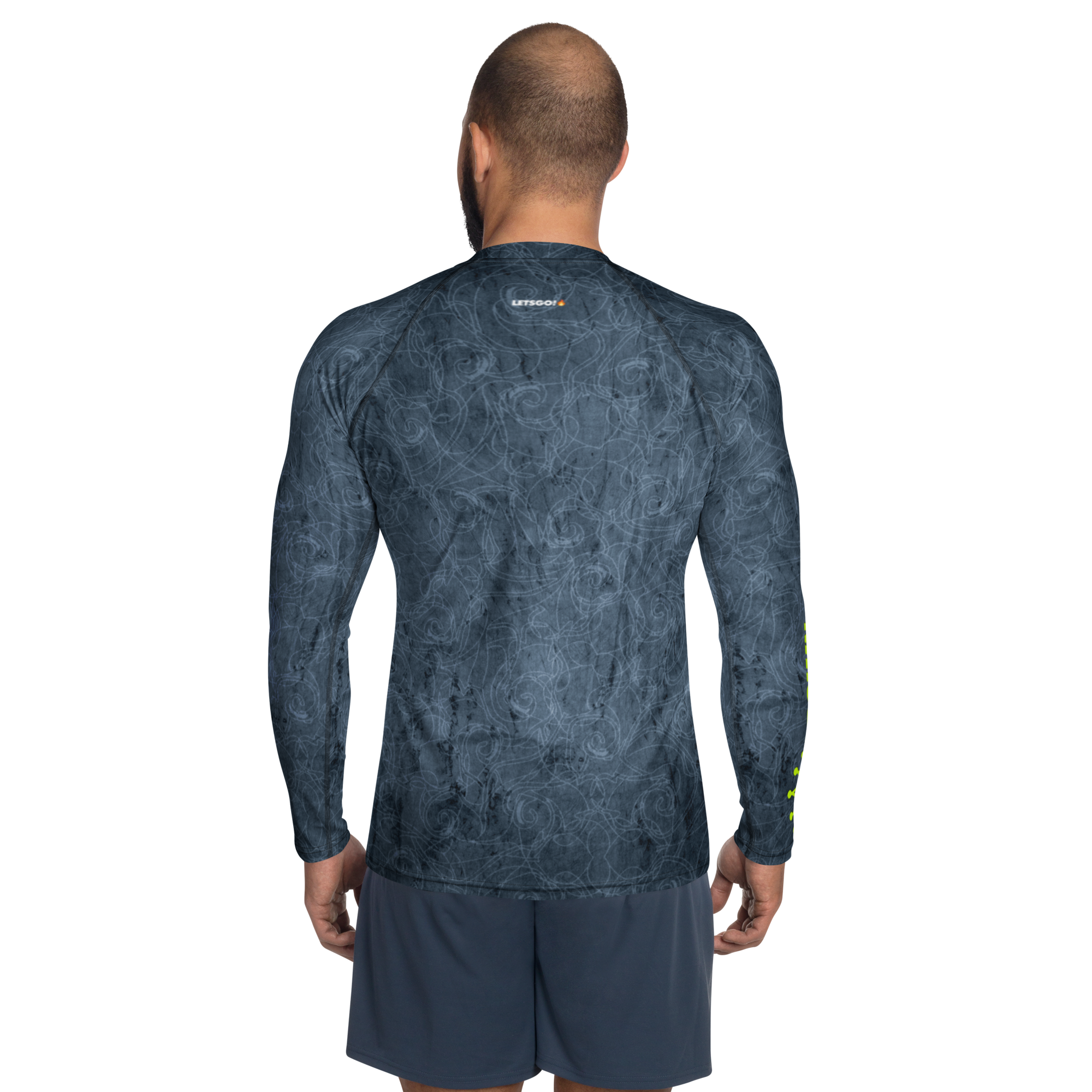 Man facing away wearing a long-sleeved shirt with gray swirling patterns and gray shorts against a black background.