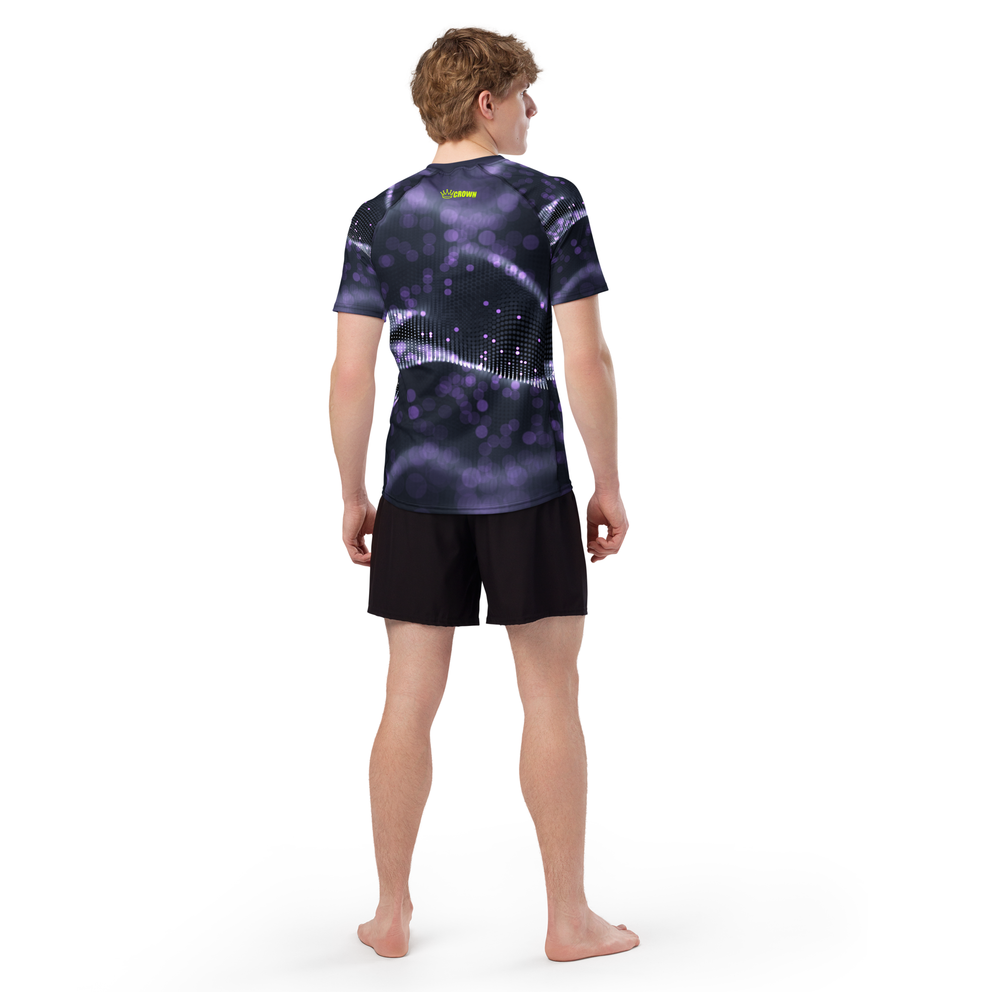 A man wearing a purple and black t-shirt and black shorts stands with his back to the viewer.
