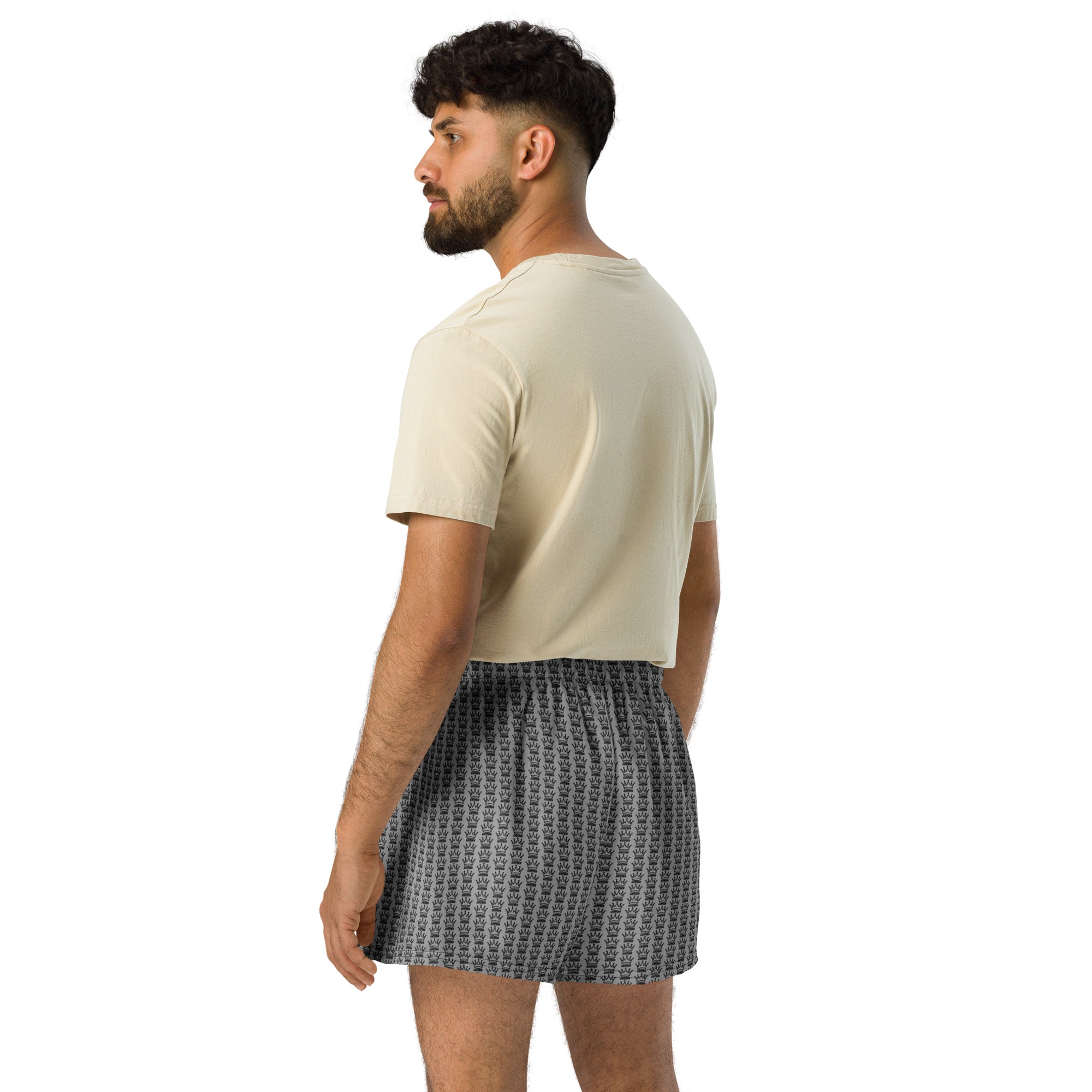 Man wearing beige t-shirt and patterned boxer shorts, viewed from the back.