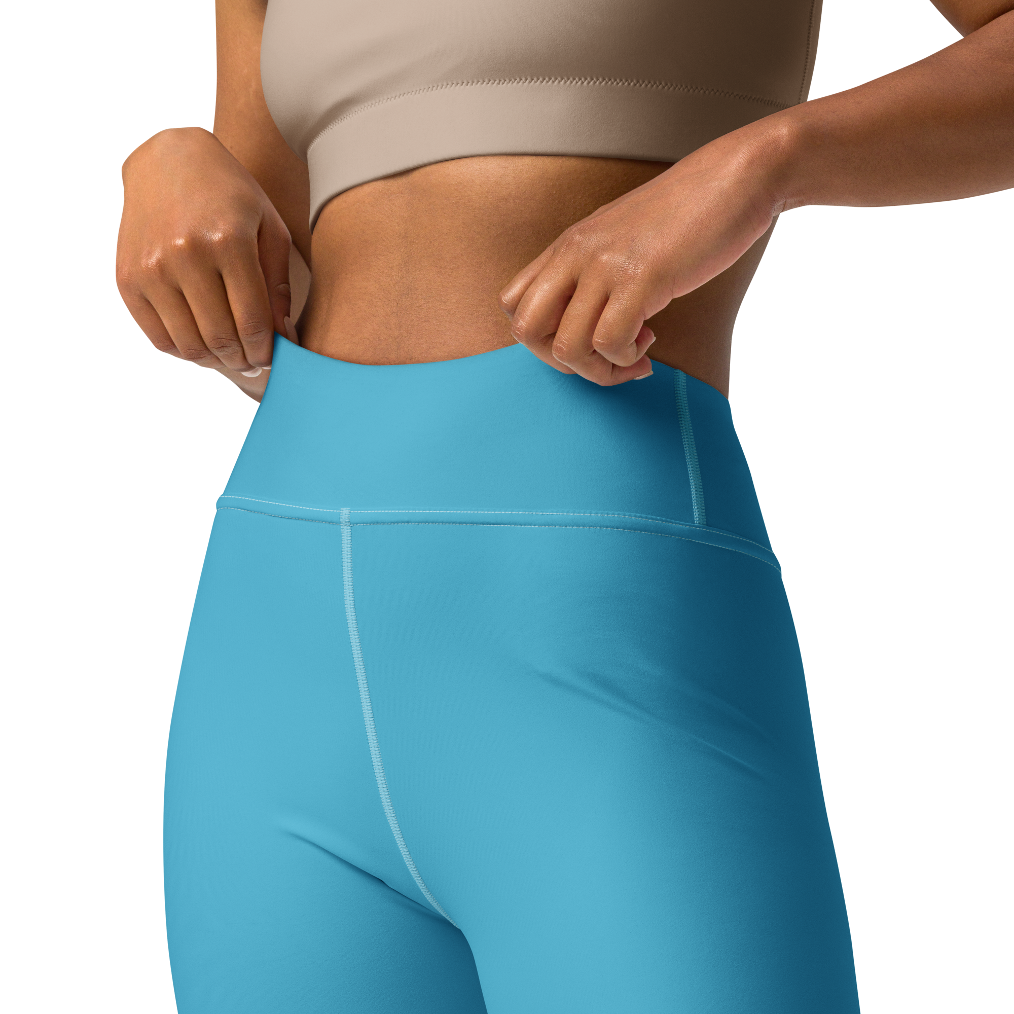 Close-up of a woman adjusting blue leggings and wearing a beige sports bra.