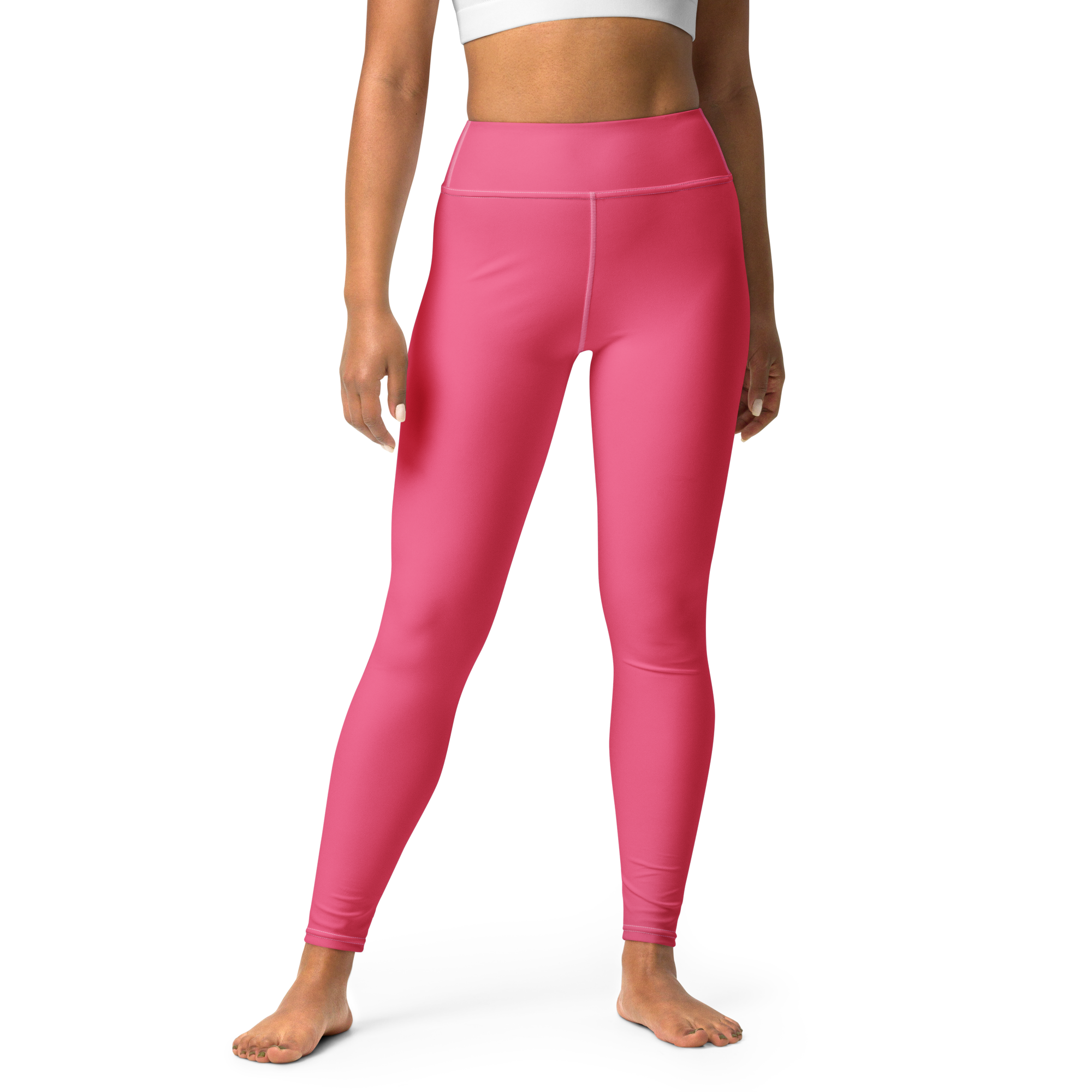 Person wearing pink leggings and a white sports bra standing against a black background.