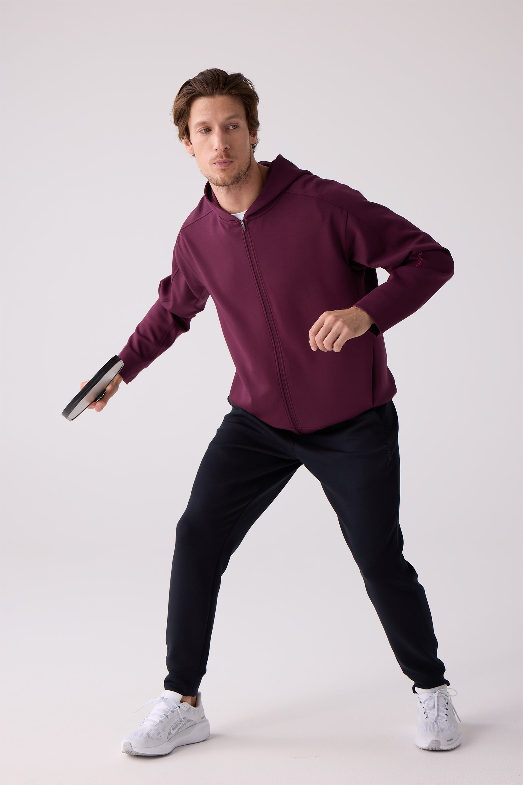 Burgundy crew sweatshirt by Centerline Athletics with a smooth, relaxed fit, styled with dark pants and white sneakers, holding a black paddle.