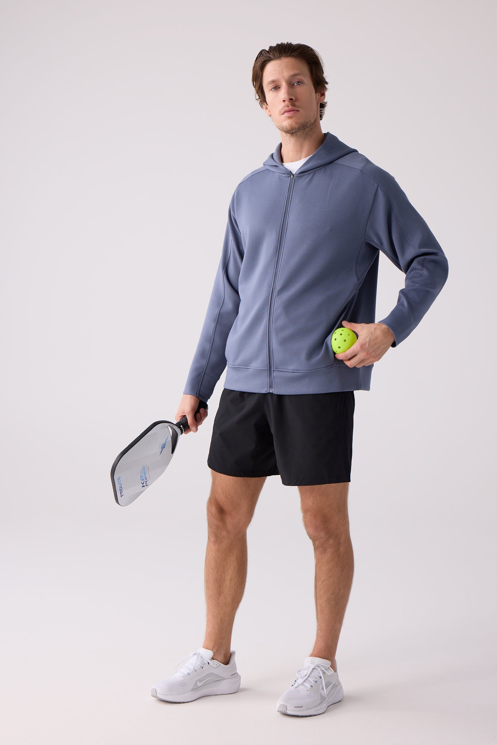 Dusty blue unisex long sleeve by Centerline Athletics, a hooded full-zip on a man holding a pickleball paddle and ball.