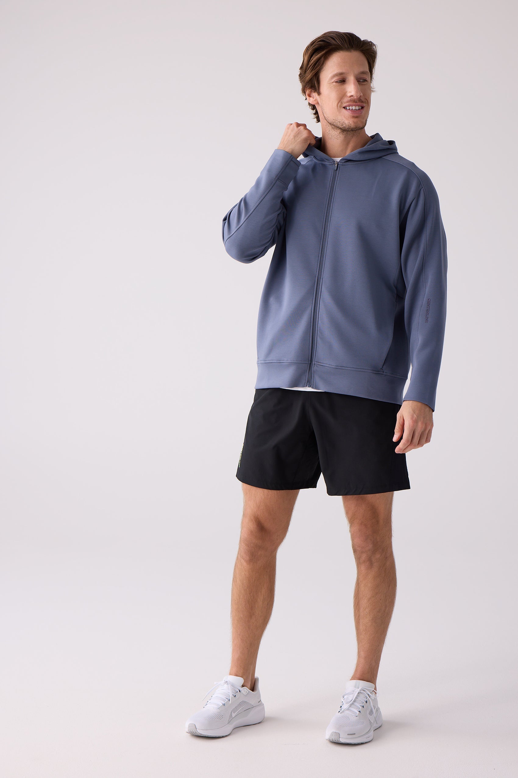 Dusty blue unisex crew sweatshirt by Centerline Athletics, made from smooth fabric with ribbed cuffs, worn by a man with black shorts and white sneakers.