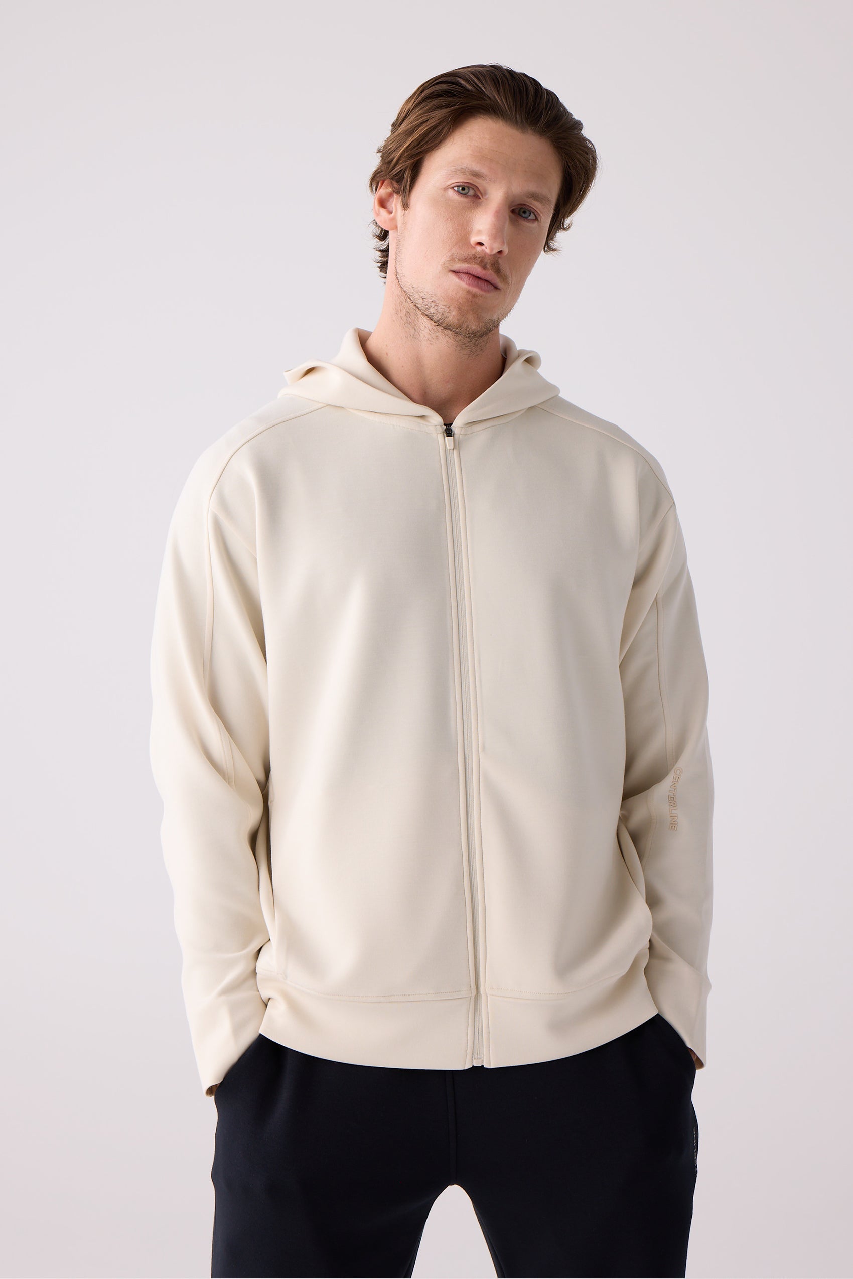 Cream unisex crew sweatshirt by Centerline Athletics with smooth fabric, subtle logo on sleeve, worn with black pants.
