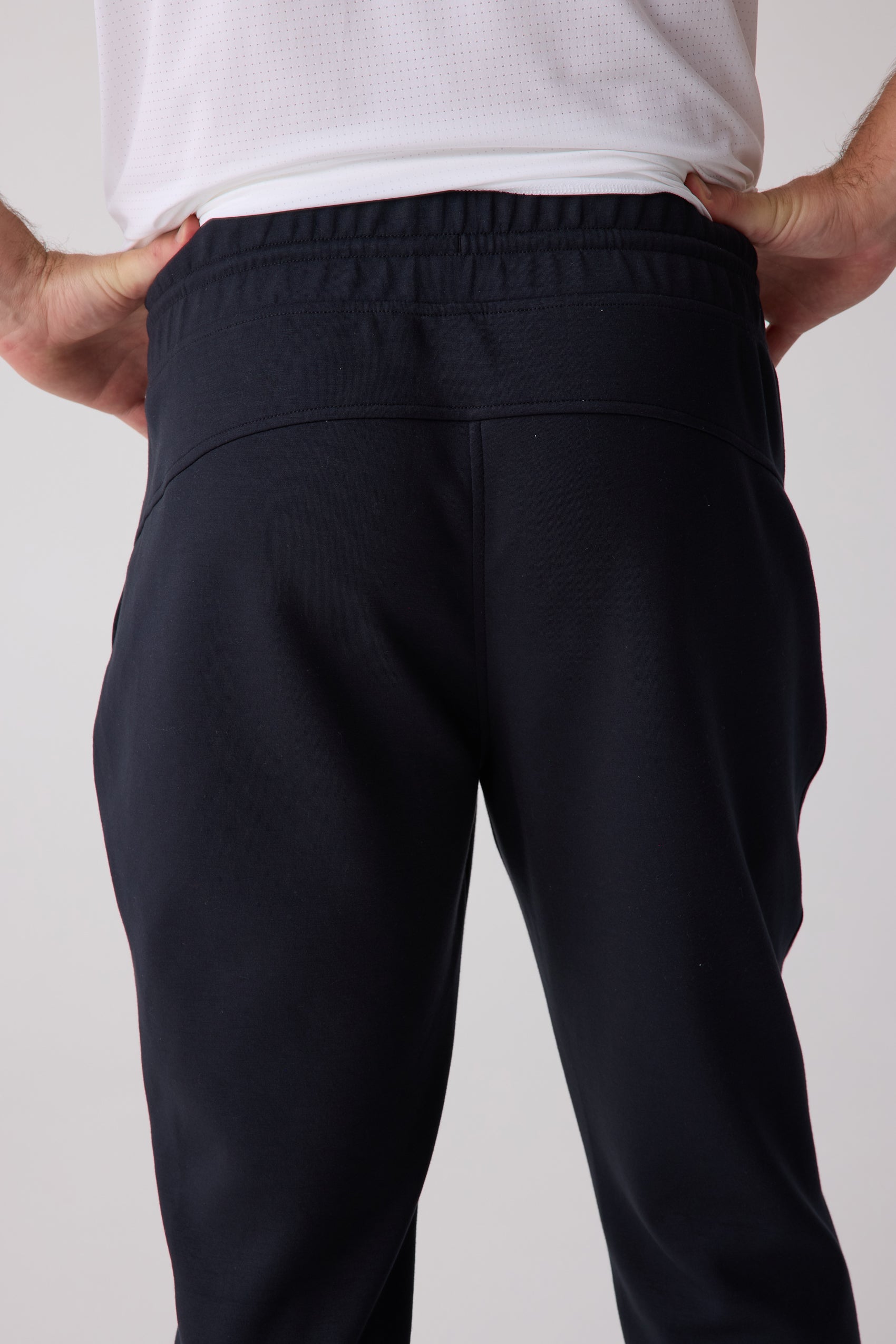 Navy Men's Après Jogger by Centerline Athletics, back view showcasing an elastic waistband, worn with a white perforated shirt.