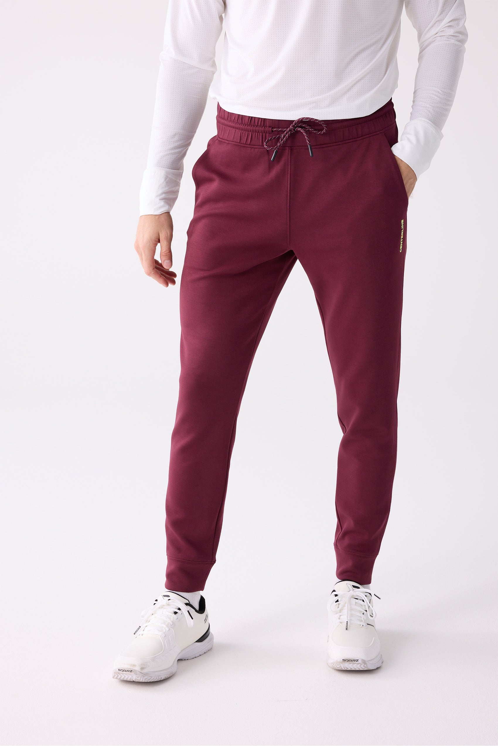 Maroon Men's Jogger Pants by Centerline Athletics, with elastic speckled drawstring waist, ribbed cuffs, and subtle yellow vertical branding, styled with a white long-sleeve shirt and white sneakers.