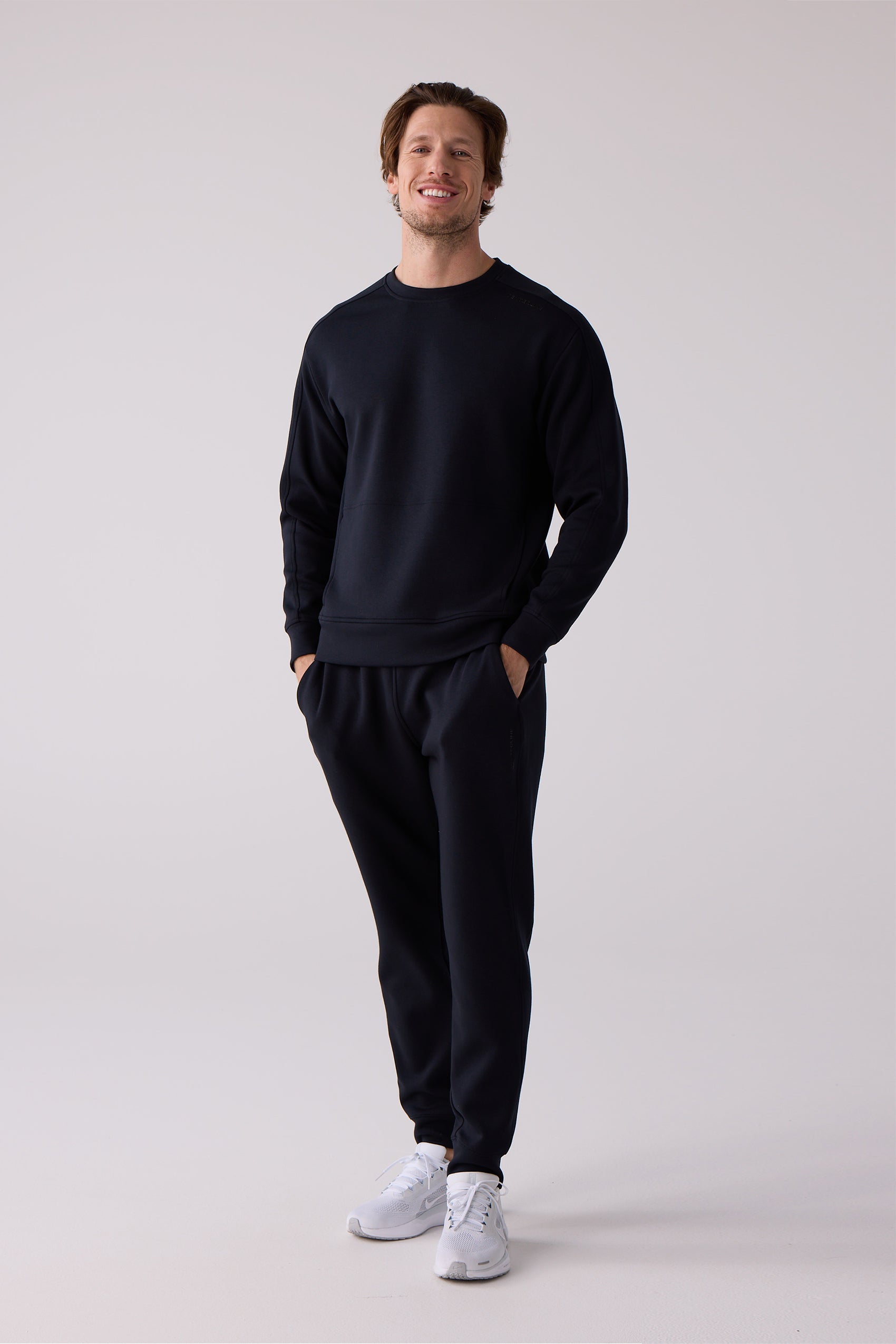 Dark navy paneled men's crew sweatshirt by Centerline Athletics, worn by a smiling man in matching sweatpants and white sneakers.