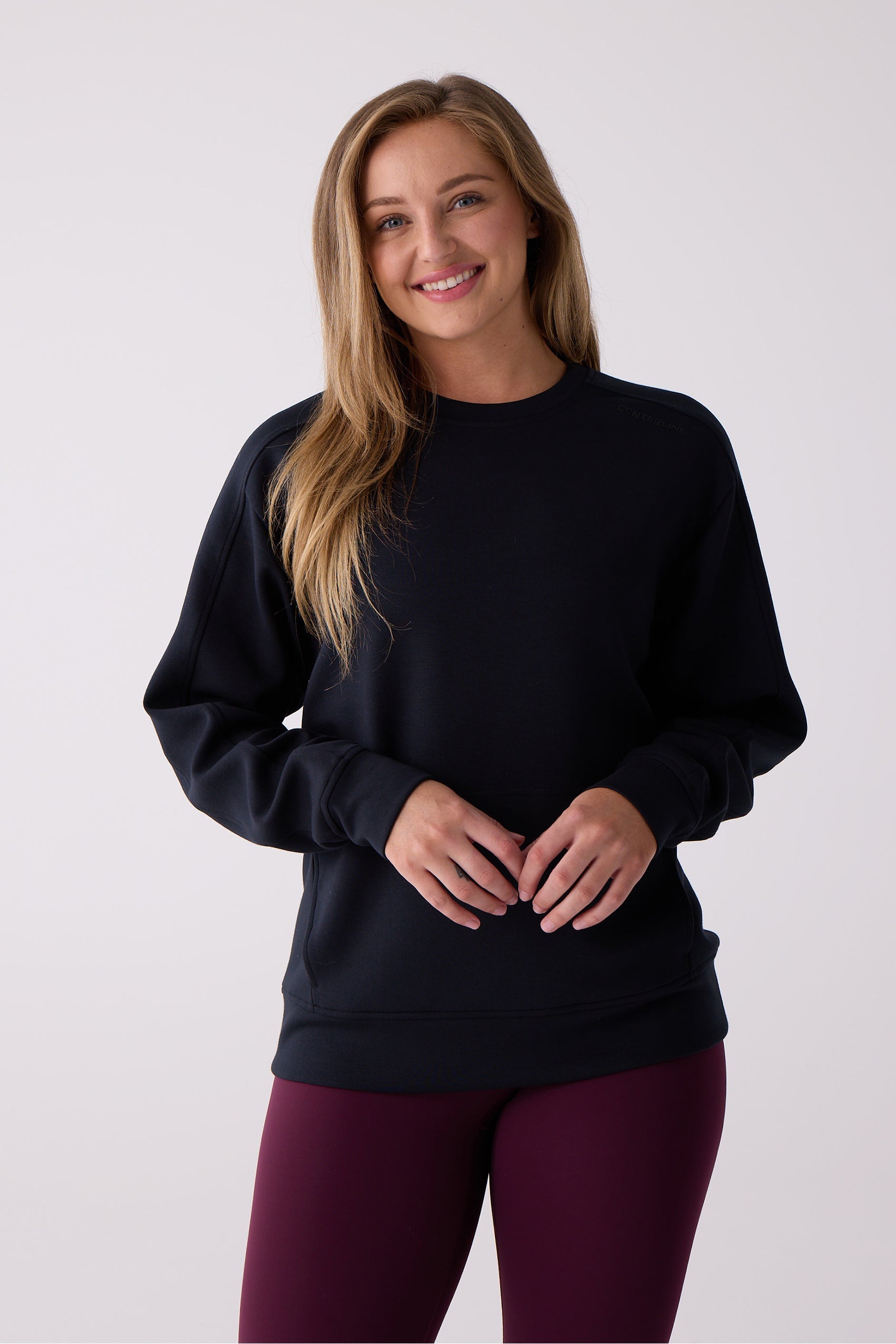 A black crew sweatshirt by Centerline Athletics featuring subtle shoulder branding, worn by a woman over burgundy leggings.
