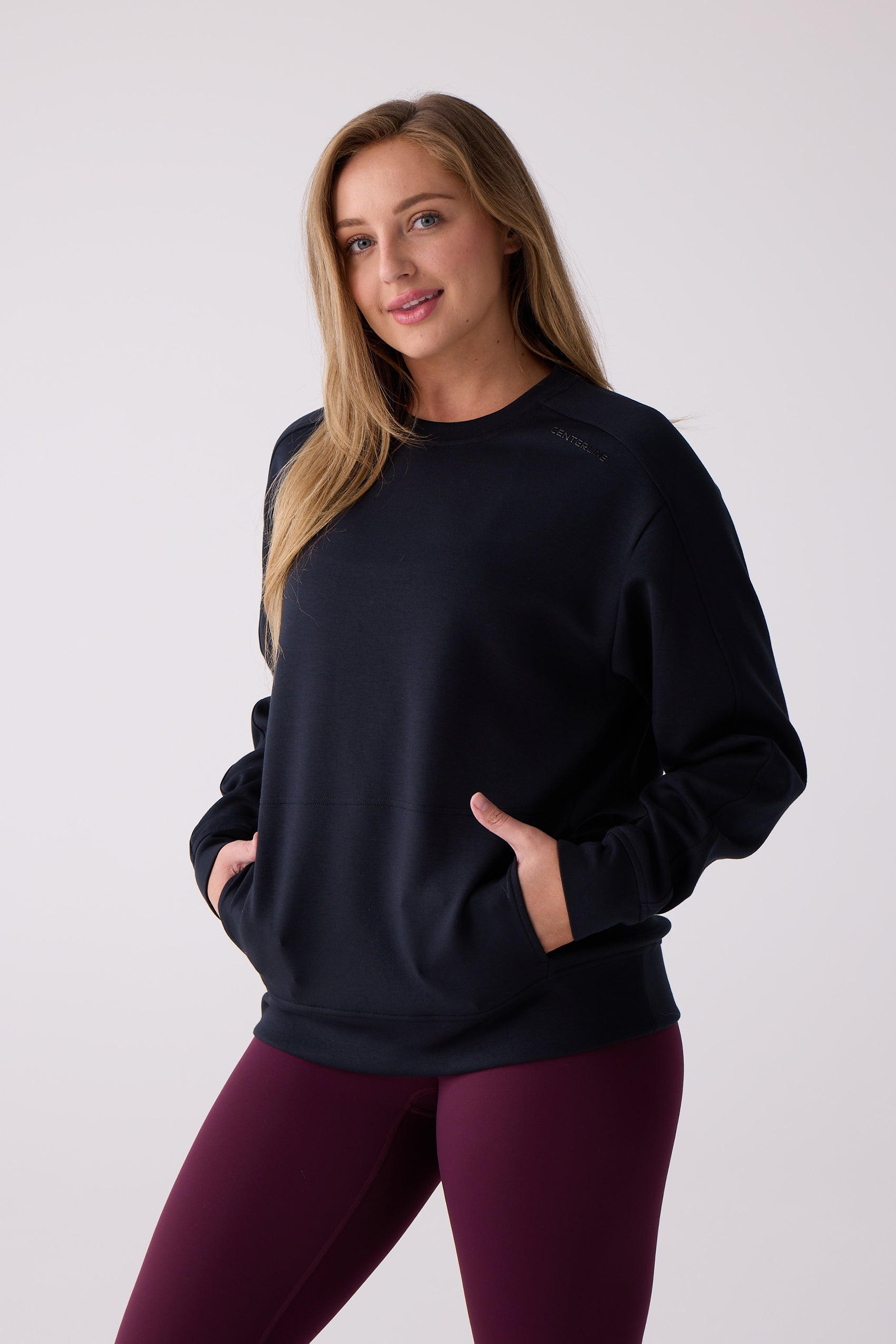 Black crew sweatshirt by Centerline Athletics with "CENTERLINE" embossed on the upper chest and hands in front pockets, worn with burgundy leggings.