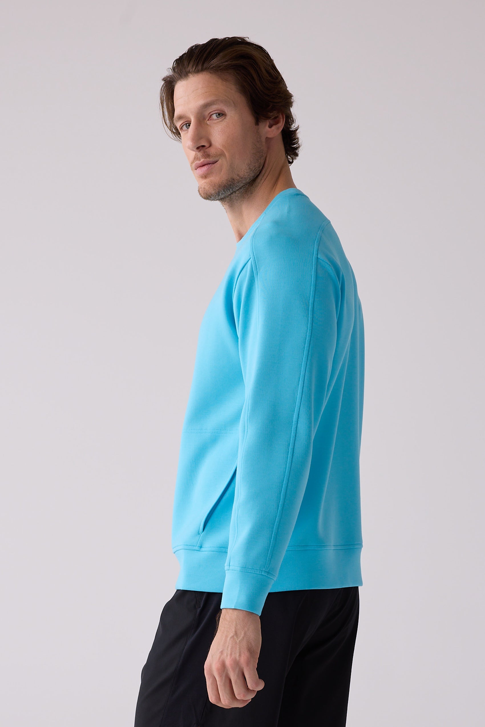 Bright blue men's crew sweatshirt by Centerline Athletics, featuring raglan sleeves and a side pocket, shown in a side view.