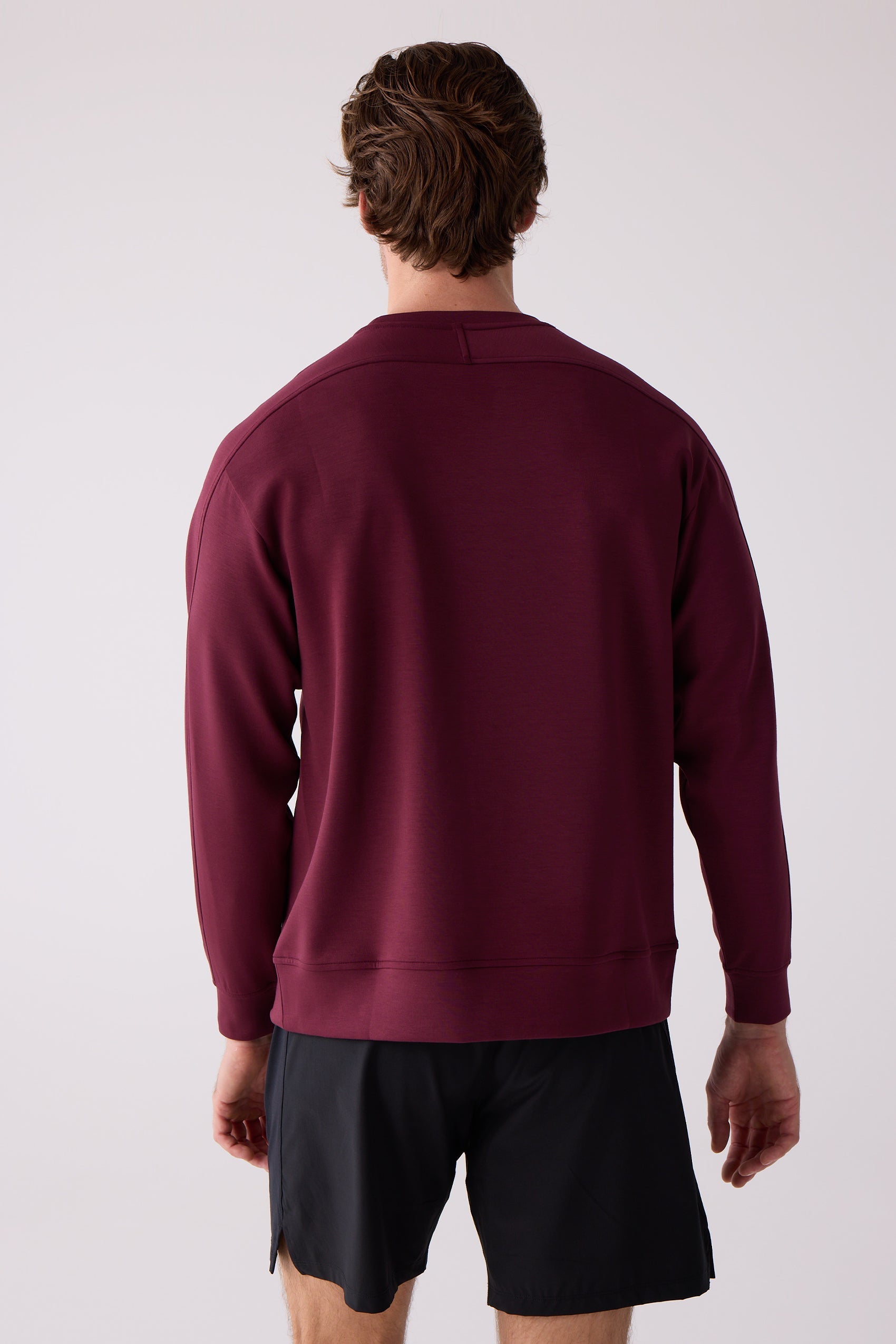 Maroon Men's Crew Sweatshirt by Centerline Athletics, back view with seam details and ribbed cuffs, worn with black shorts.