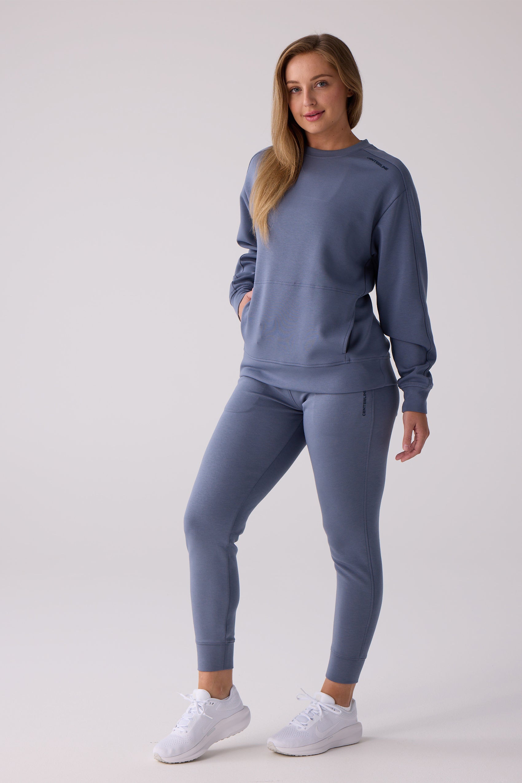 Soft slate blue Women's Crew Sweatshirt by Centerline Athletics, featuring a shoulder logo and front kangaroo pocket, paired with matching joggers.