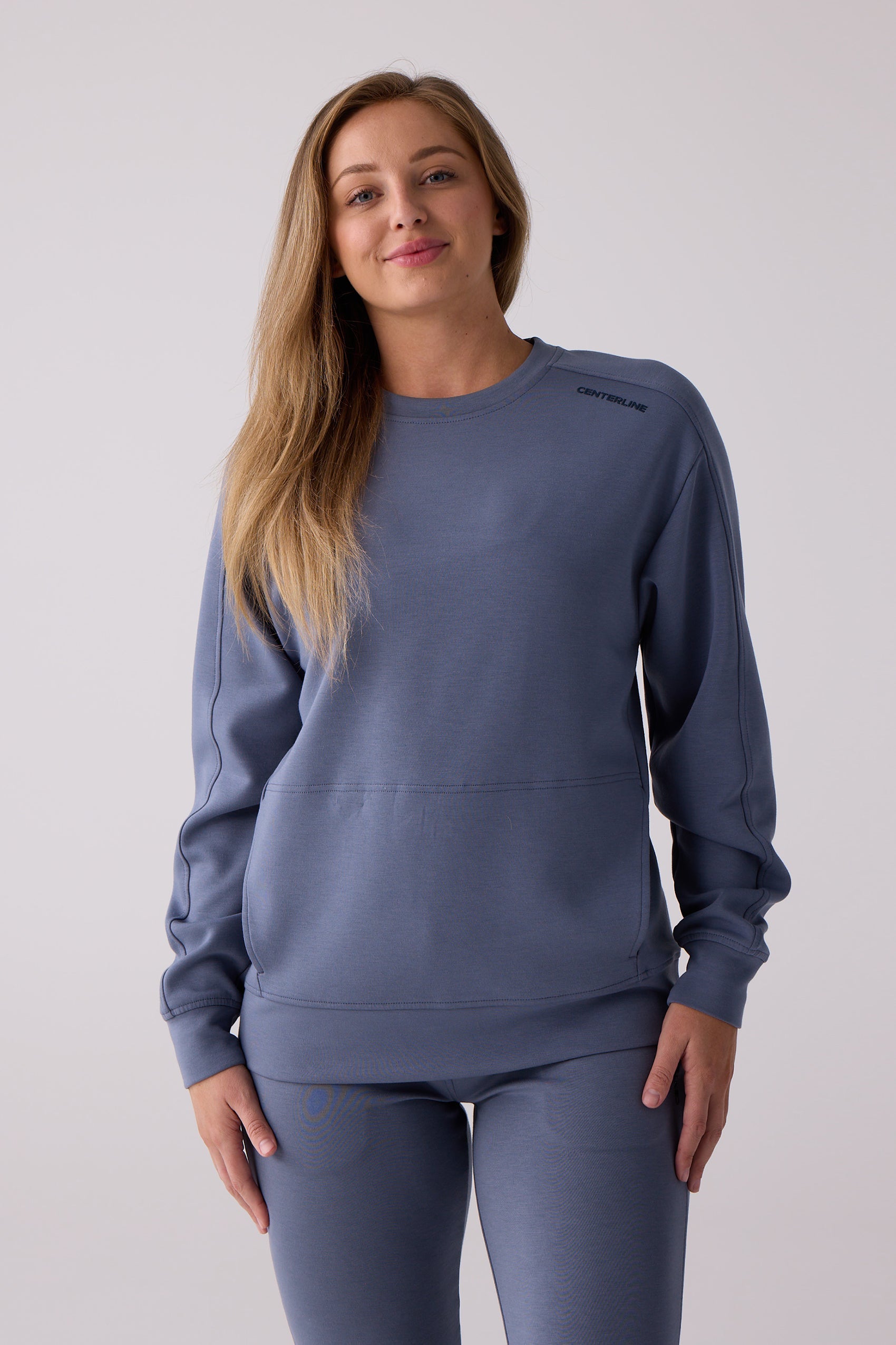 Dusty blue women's crew sweatshirt by Centerline Athletics with a front pocket, visible shoulder logo, and matching pants.